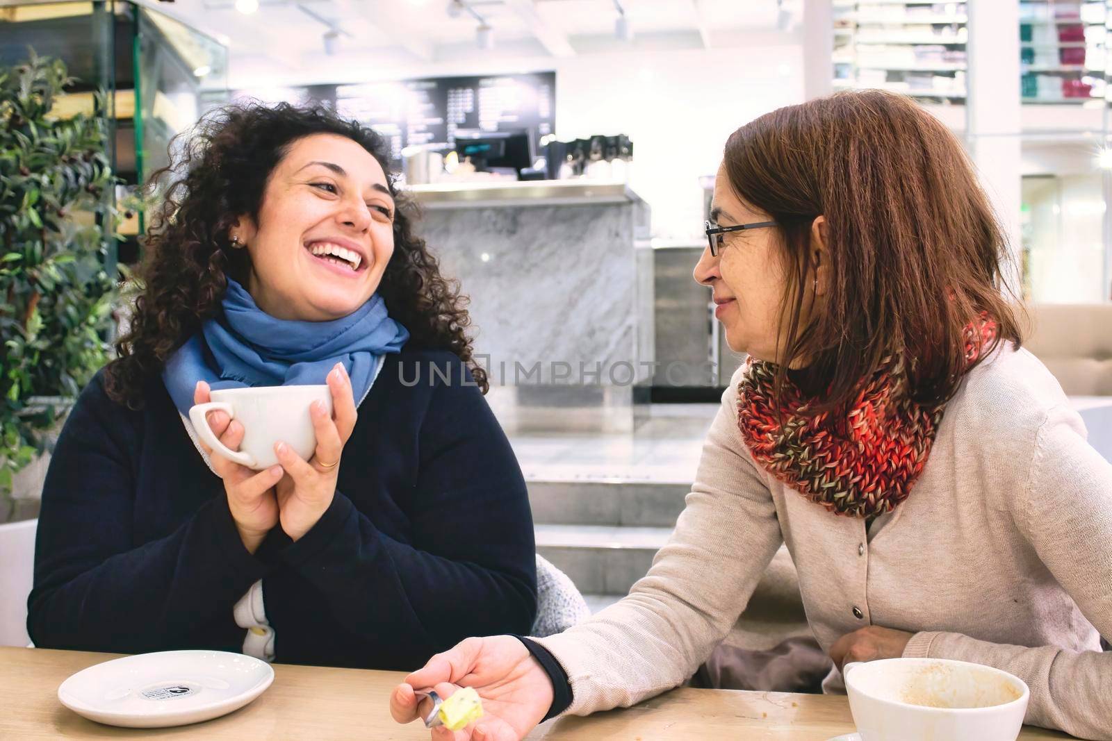 Two women of different generations having a good time enjoying a cup of coffee in a cafeteria by tennesseewitney