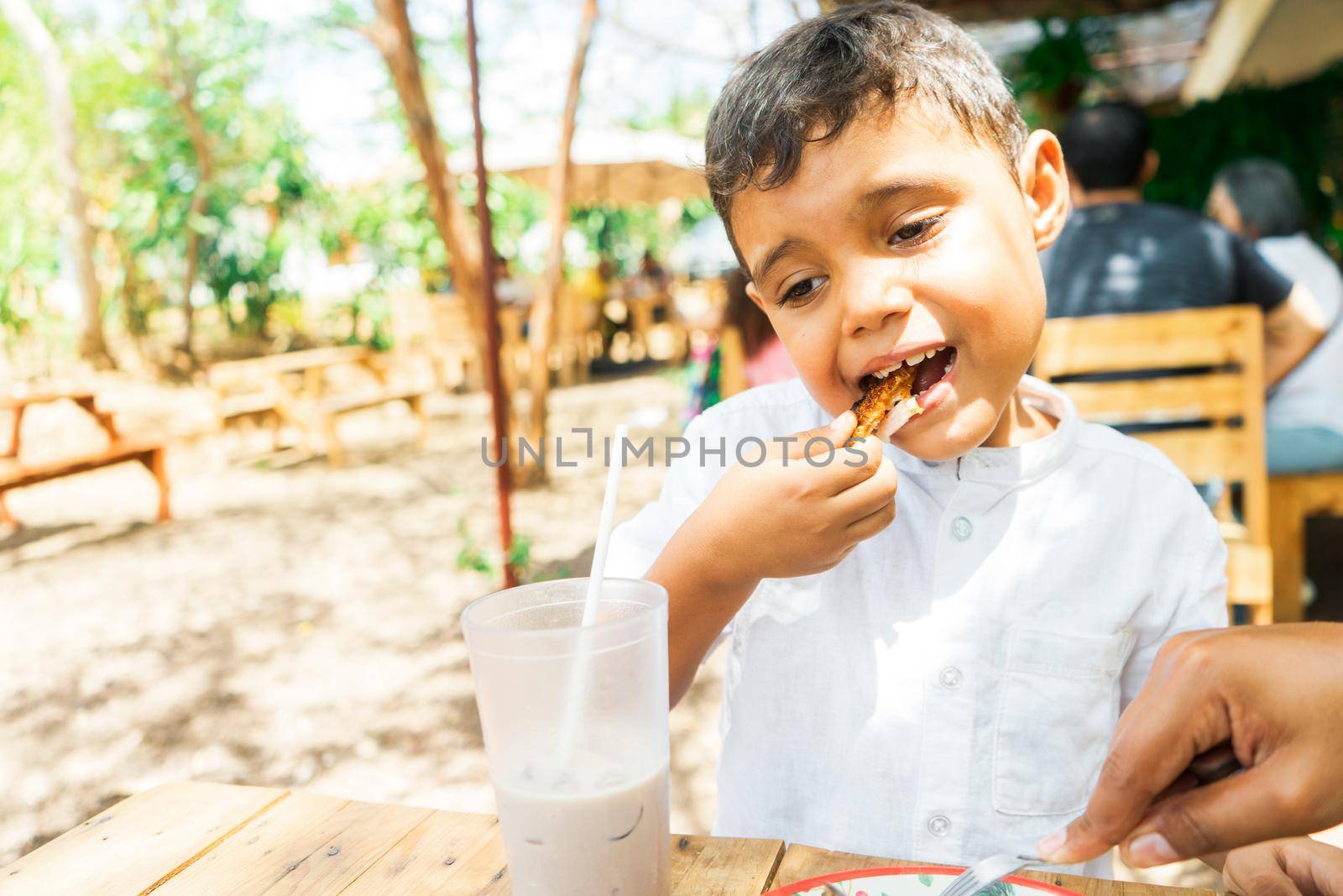 Latin boy eating pork belly or chicharron in a country restaurant in Managua Nicaragua