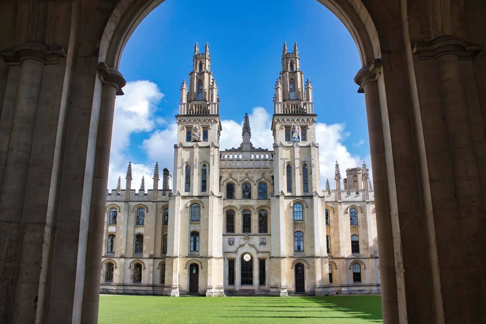 All Souls college, Oxford university - front view of entrance with towers and the green lawn from an archway