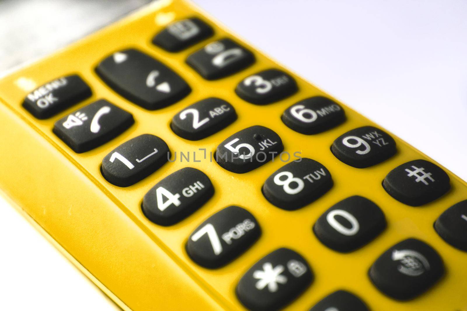 Closeup on keypad of a yellow hand-held phone by tennesseewitney