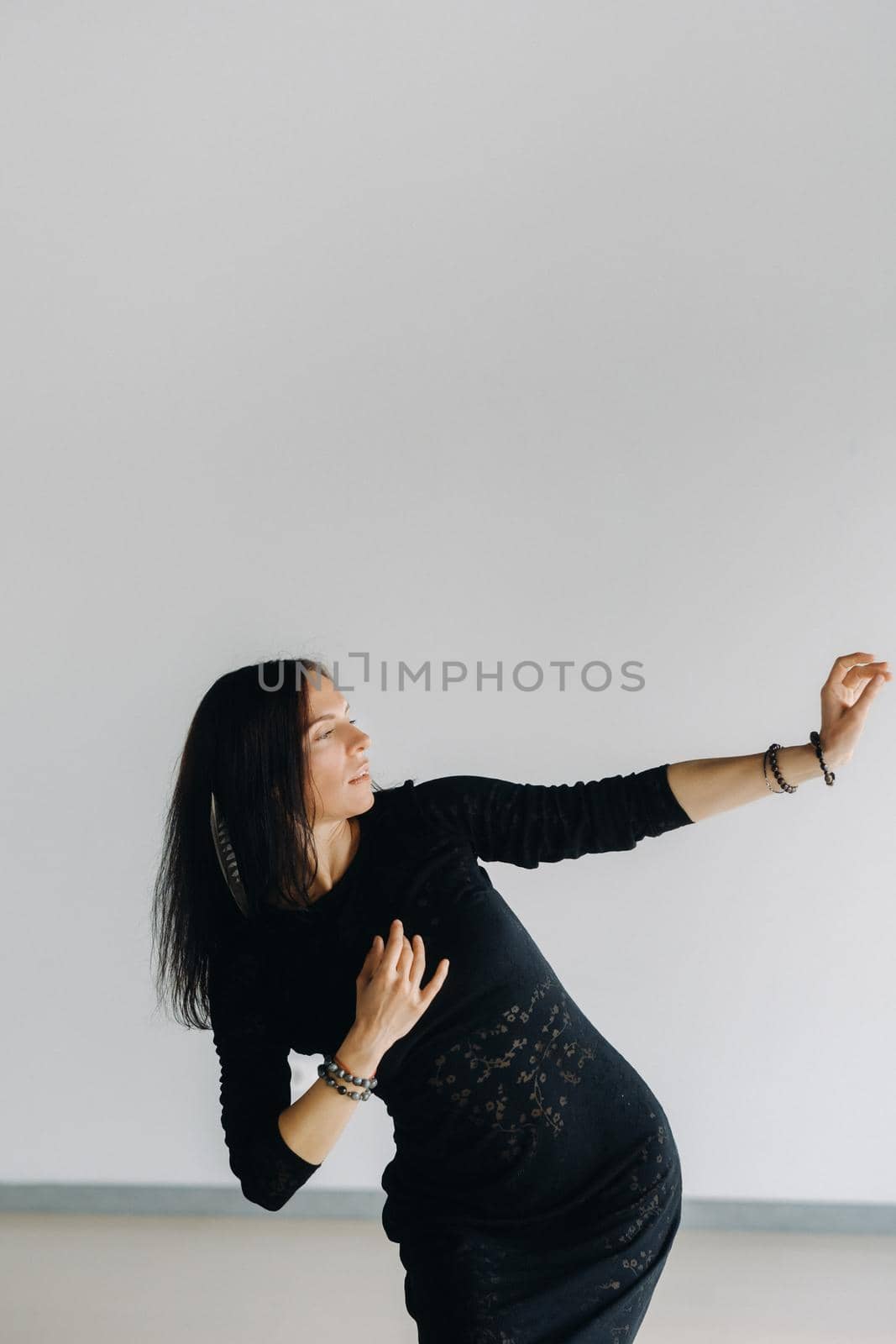 A girl in a black dress moves in a dance on a gray background. Dynamic dance by Lobachad