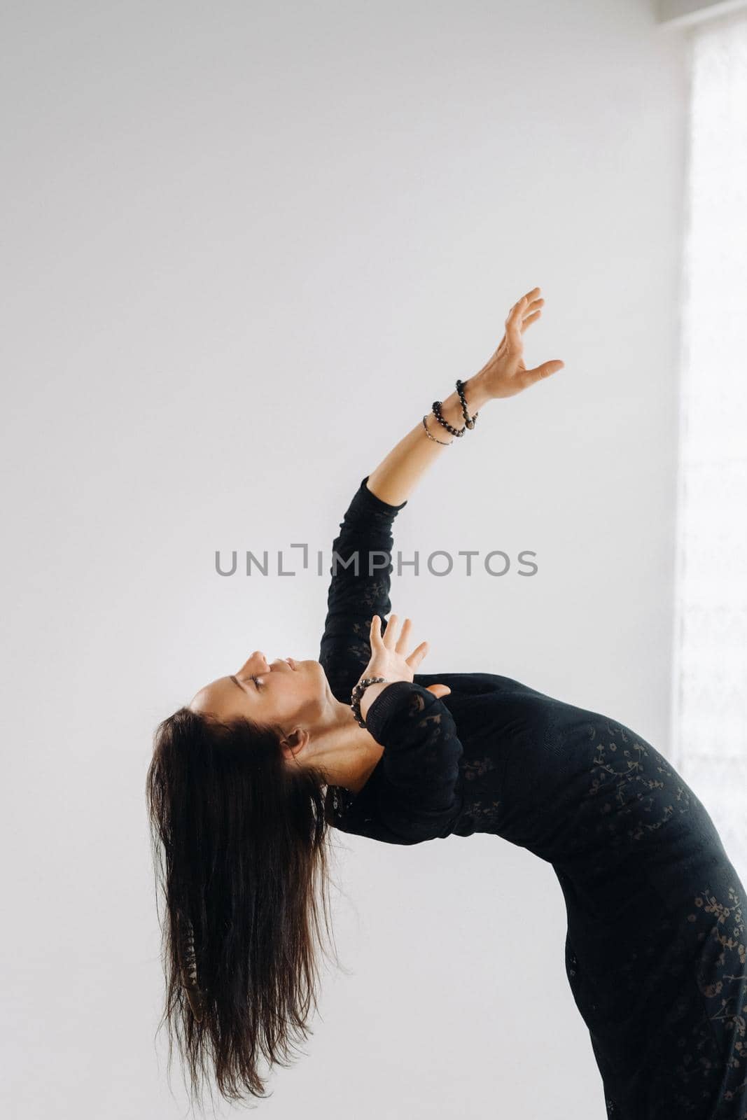 A girl in a black dress moves in a dance on a gray background. Dynamic dance,