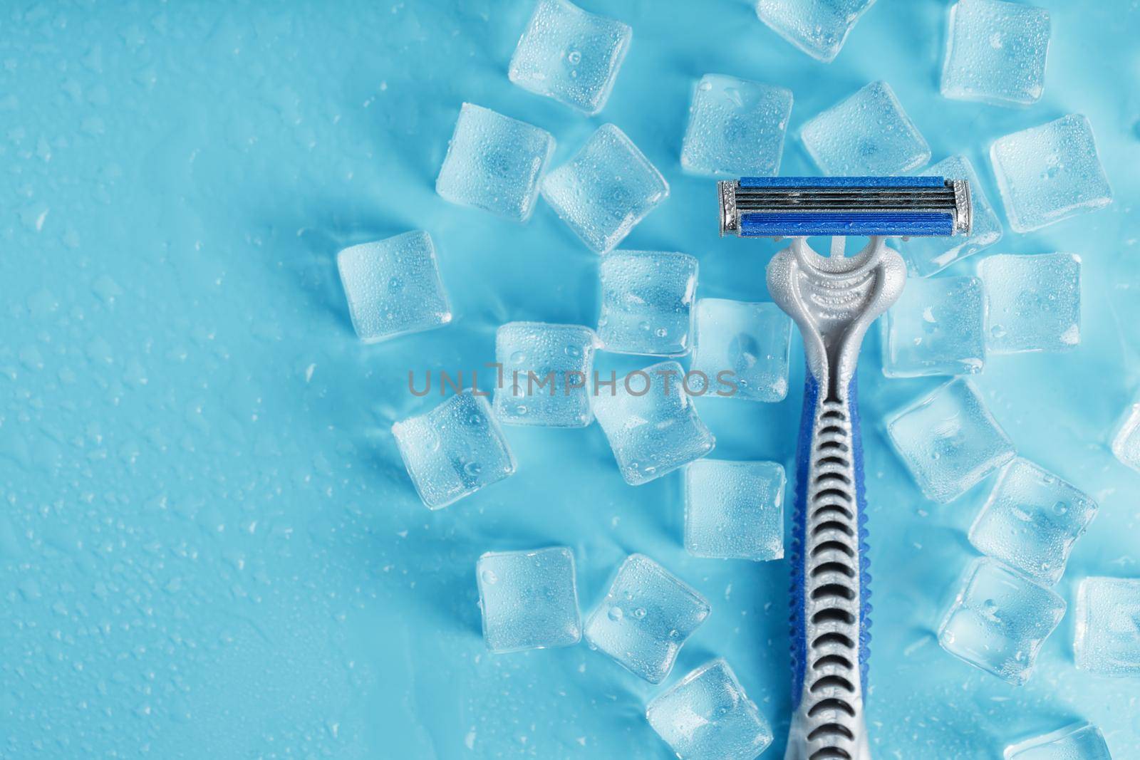 Shaving machine on a blue background with ice cubes. The concept of cleanliness and frosty freshness