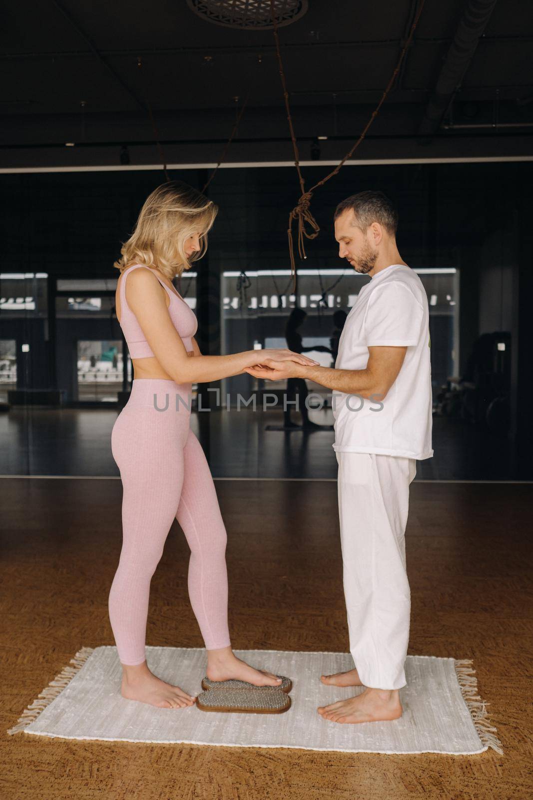 a man and a woman do yoga on boards with nails in the gym.