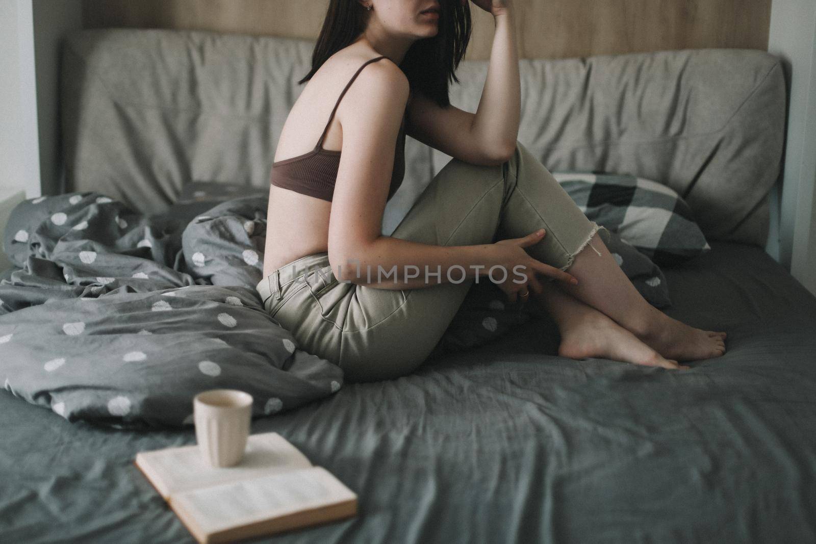 Young sexy woman portrait in bed with a book and coffee cup in the morning