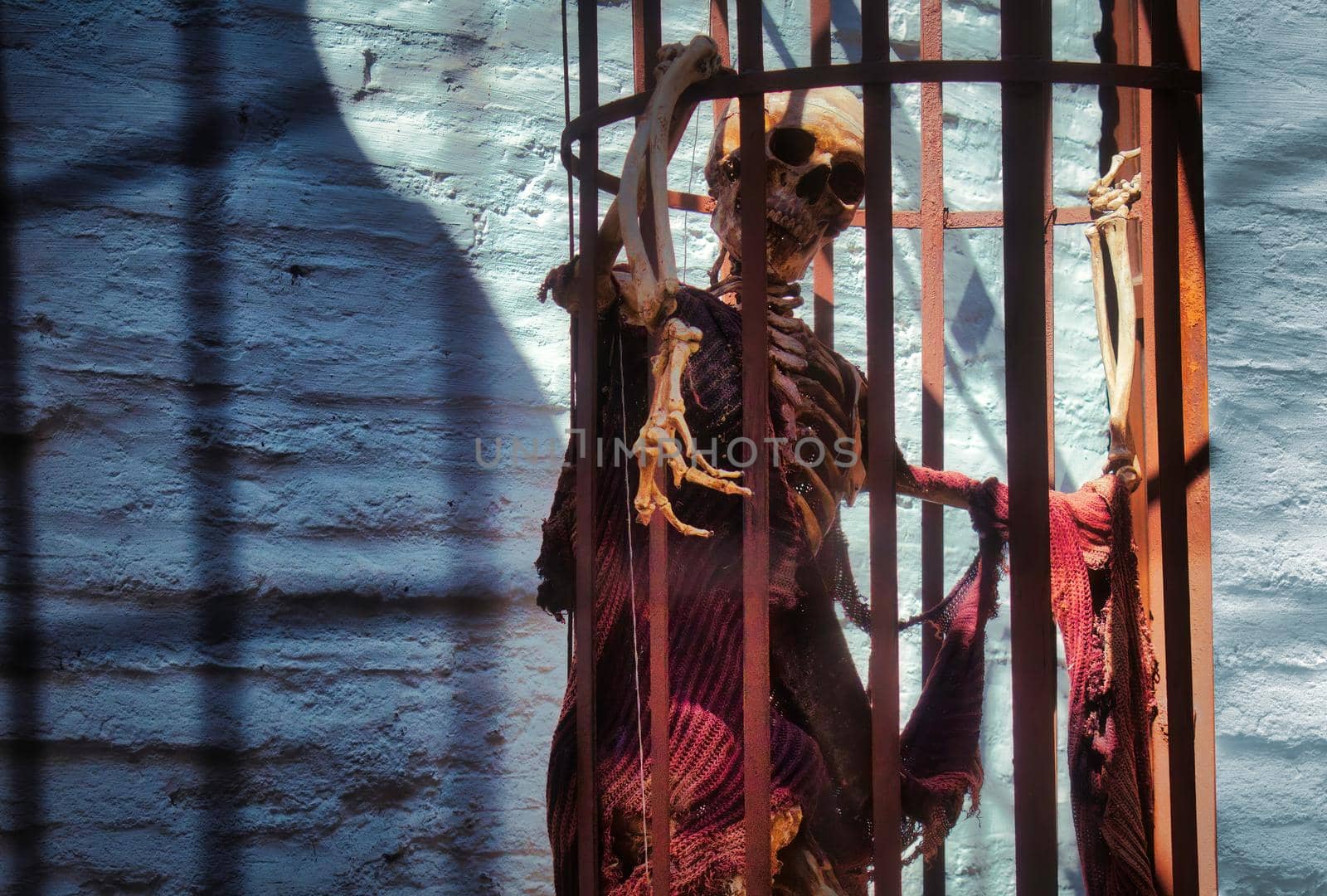 A skeleton in a hanging cage wearing rags