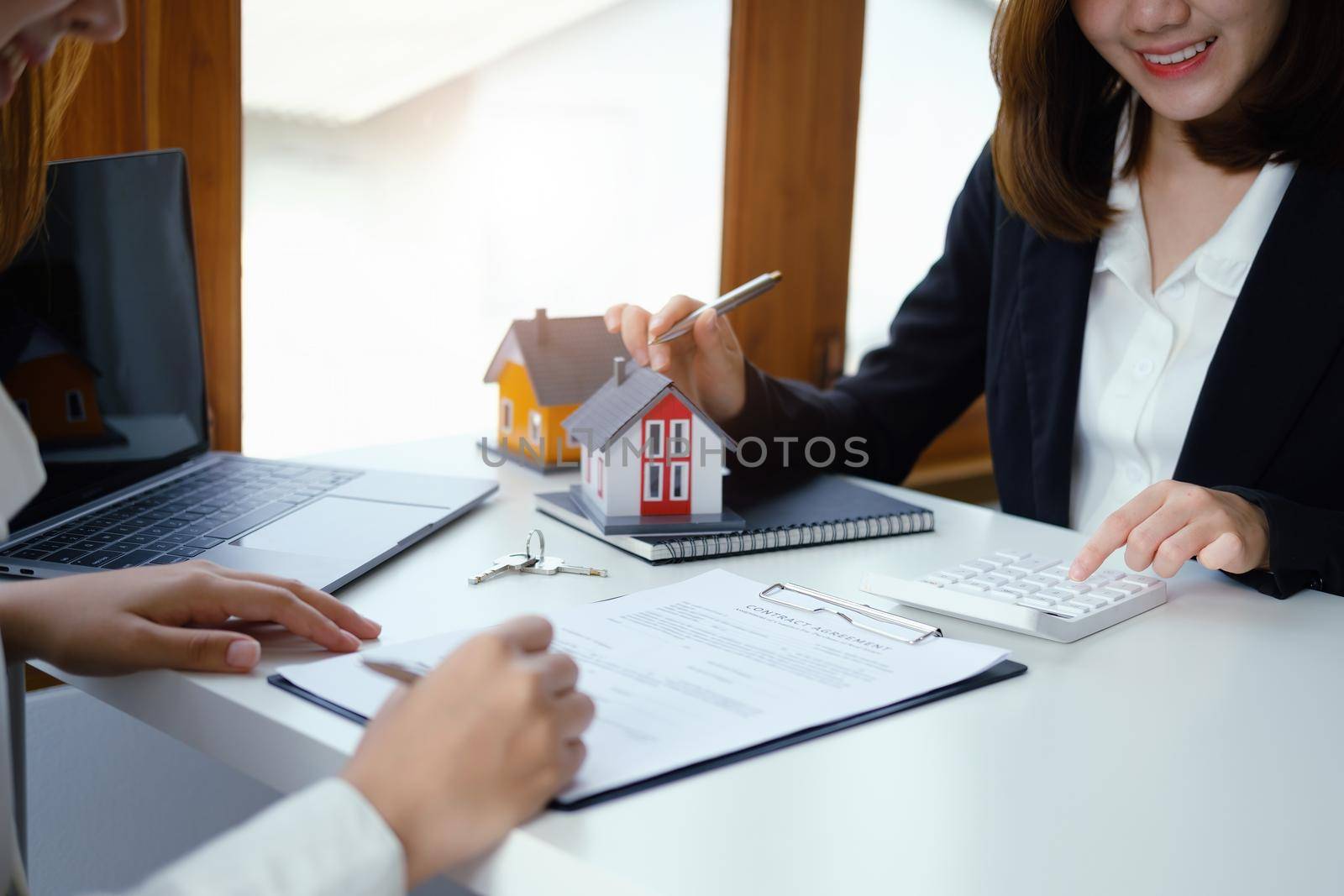 Guarantee, mortgage, contract, contract, signed, real estate agent or bank officer pointing a calculator, submits a bid with a customer to buy a home before signing to make a deal by Manastrong