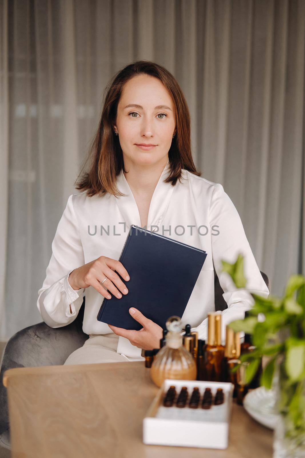 portrait of a smiling girl-woman sitting in an armchair. An aromatherapist in a white blouse is sitting in the office.