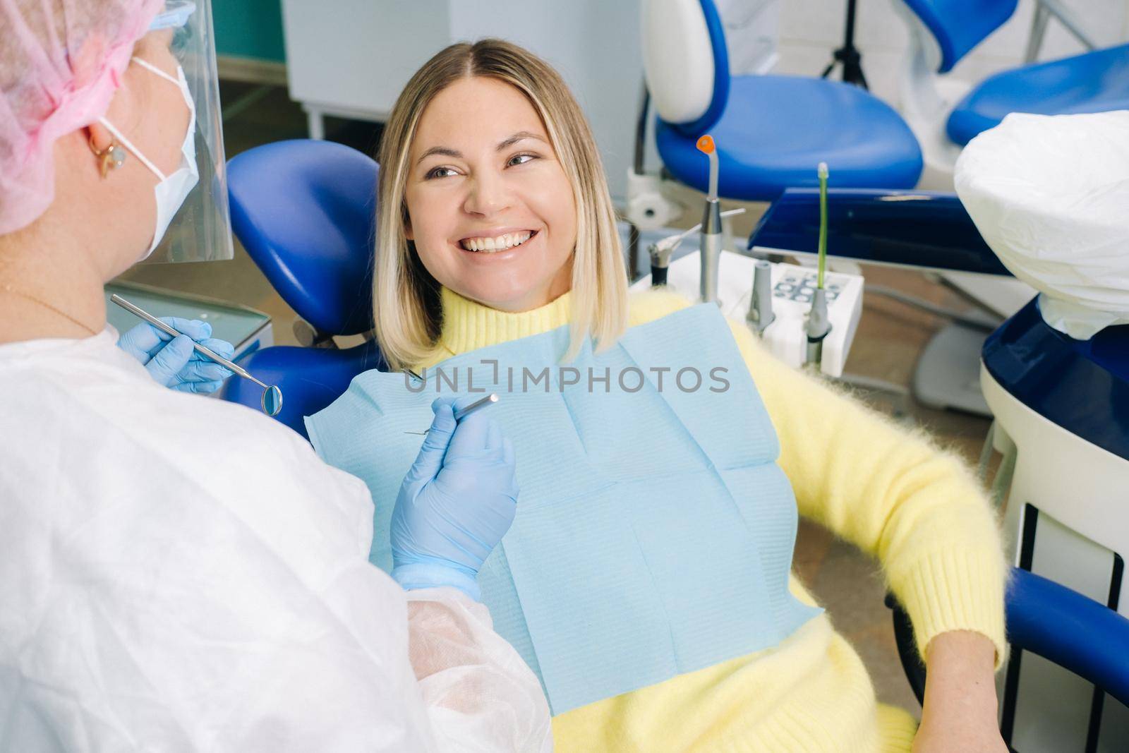 The girl smiles at the dentist and looks at her by Lobachad
