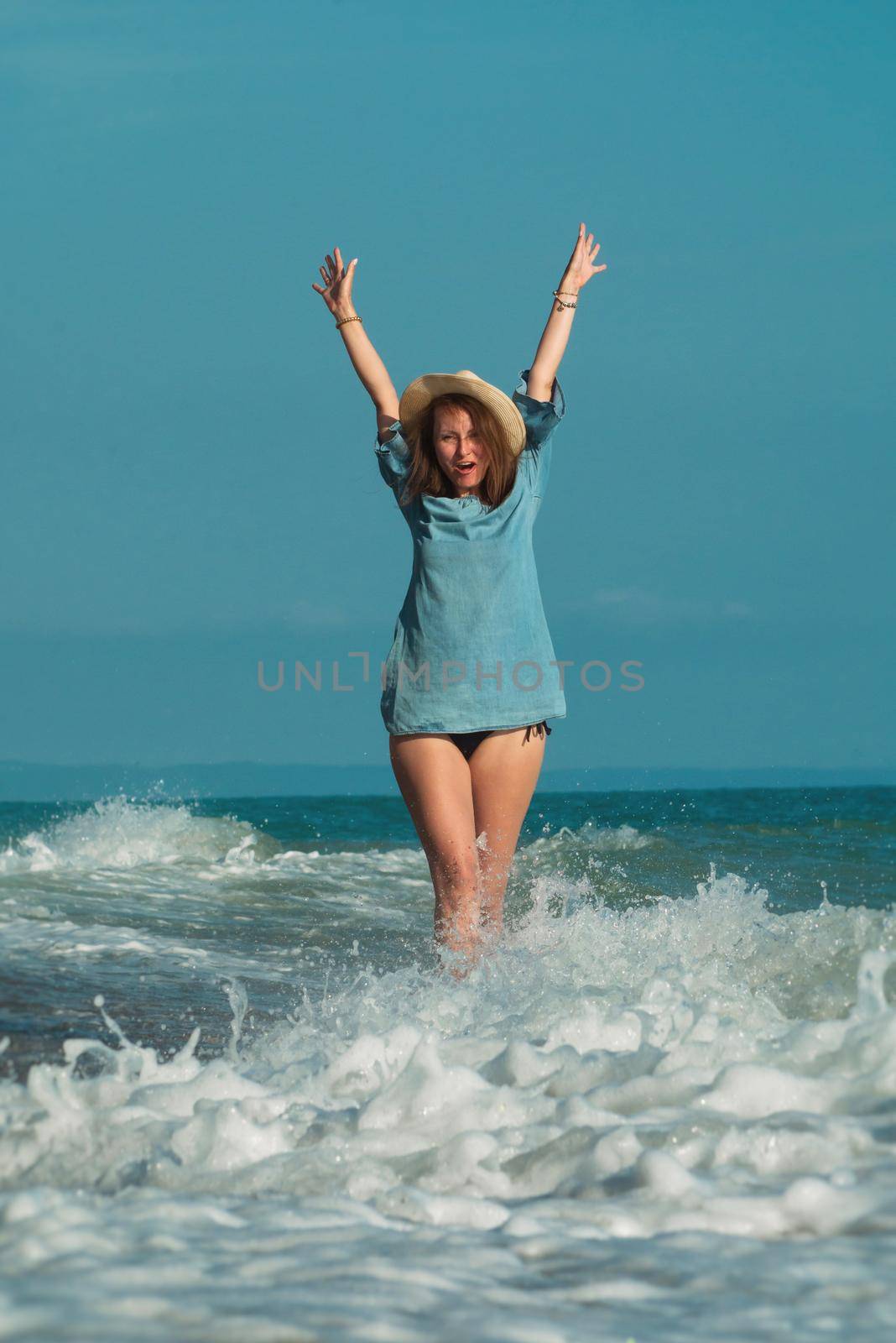 the beautiful girl in a swimsuit in summer on the seashore happily having fun on the water with emotions