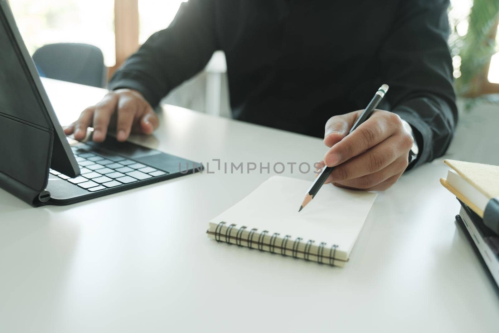 Closeup businessman working on digital tablet and laptop computer using stylus pen on white table.