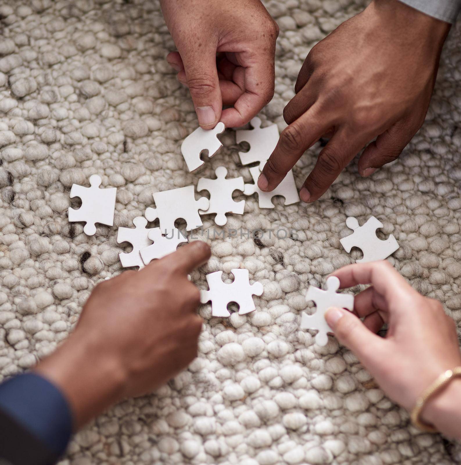 Pulling together to solve a problem. Cropped shot of a group of people fitting puzzle pieces together. by YuriArcurs