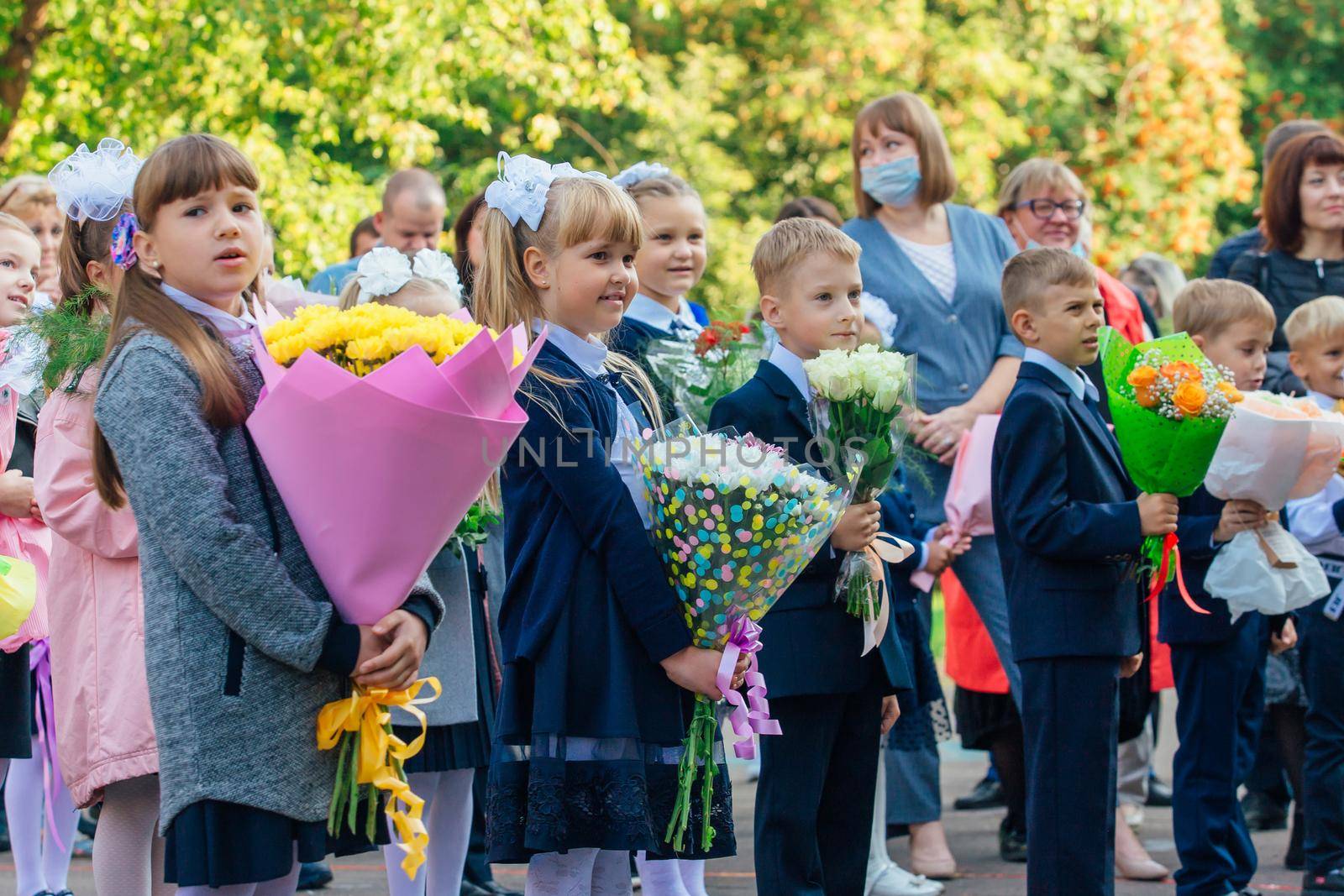 NOVOKUZNETSK, KEMEROVO REGION, RUSSIA - SEP, 1, 2021: Meeting with the first-grade pupils and teacher at schoolyard. The day of knowledge in Russia.