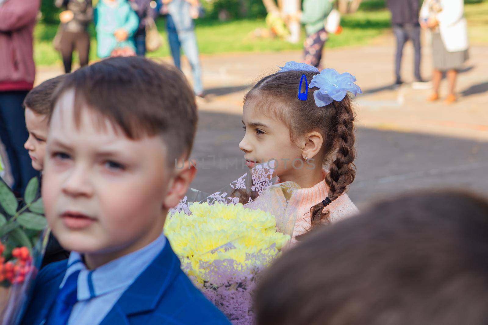 NOVOKUZNETSK, KEMEROVO REGION, RUSSIA - SEP, 1, 2021: Meeting with the first-grade pupils and teacher at schoolyard. The day of knowledge in Russia.