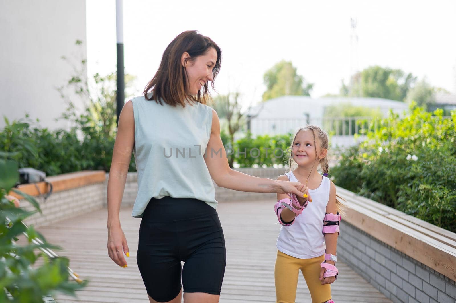 Caucasian woman teaches her daughter to skate on roller skates