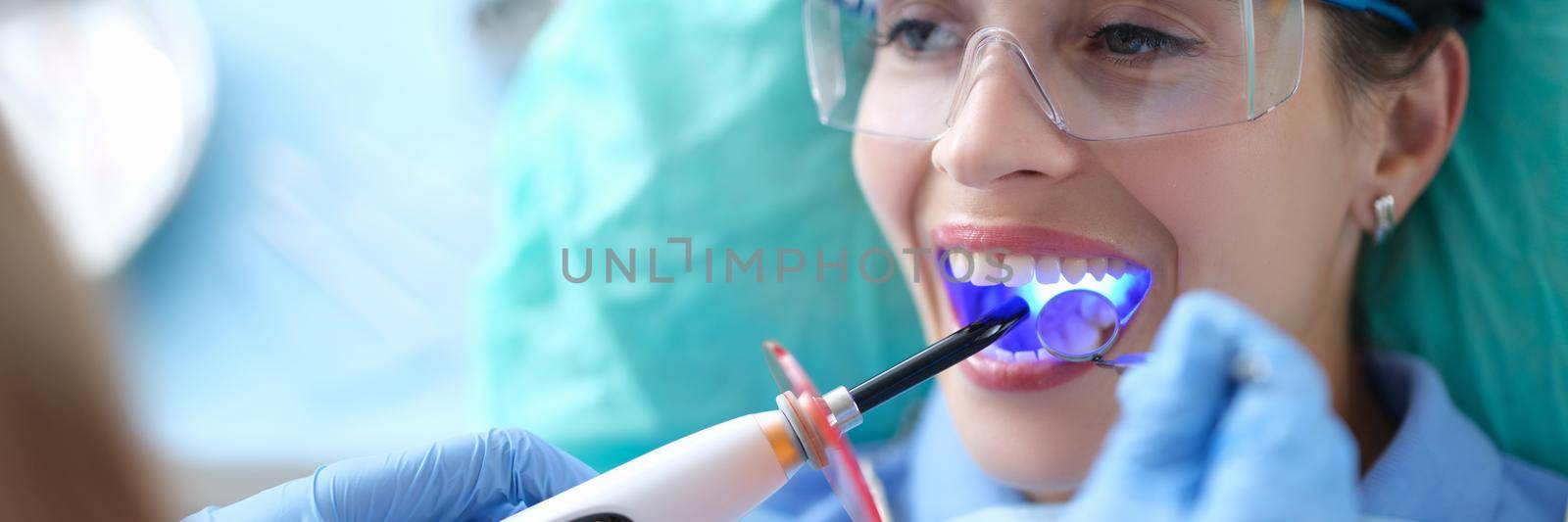 Dentist works with dental polymerization lamp in oral cavity by kuprevich