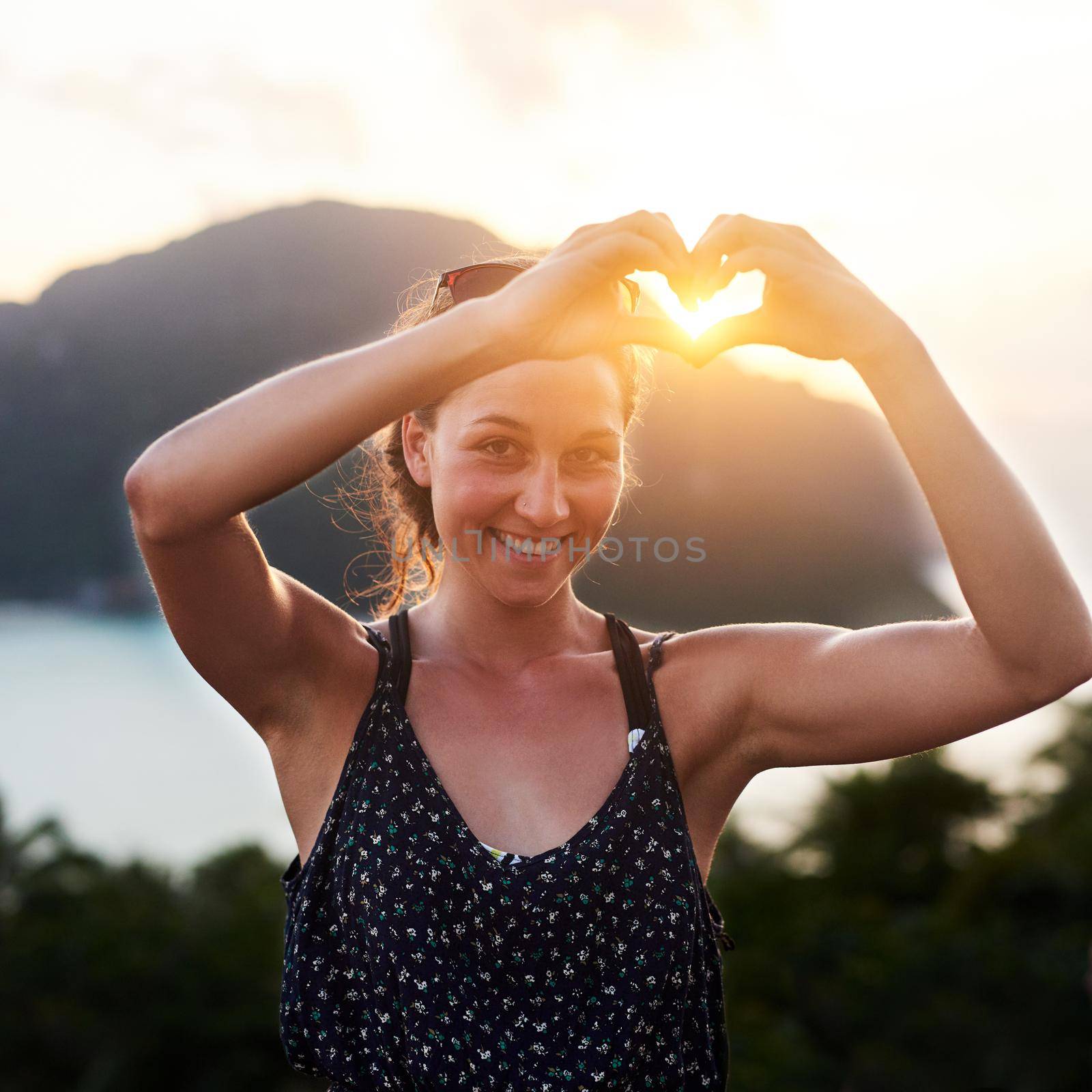Portrait of a young woman making a heart gesture outside.