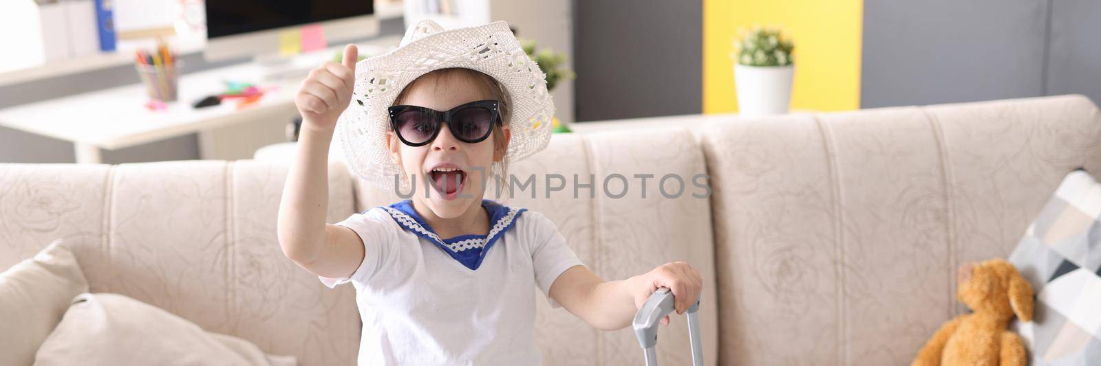Little girl in sunglasses with suitcase closeup by kuprevich