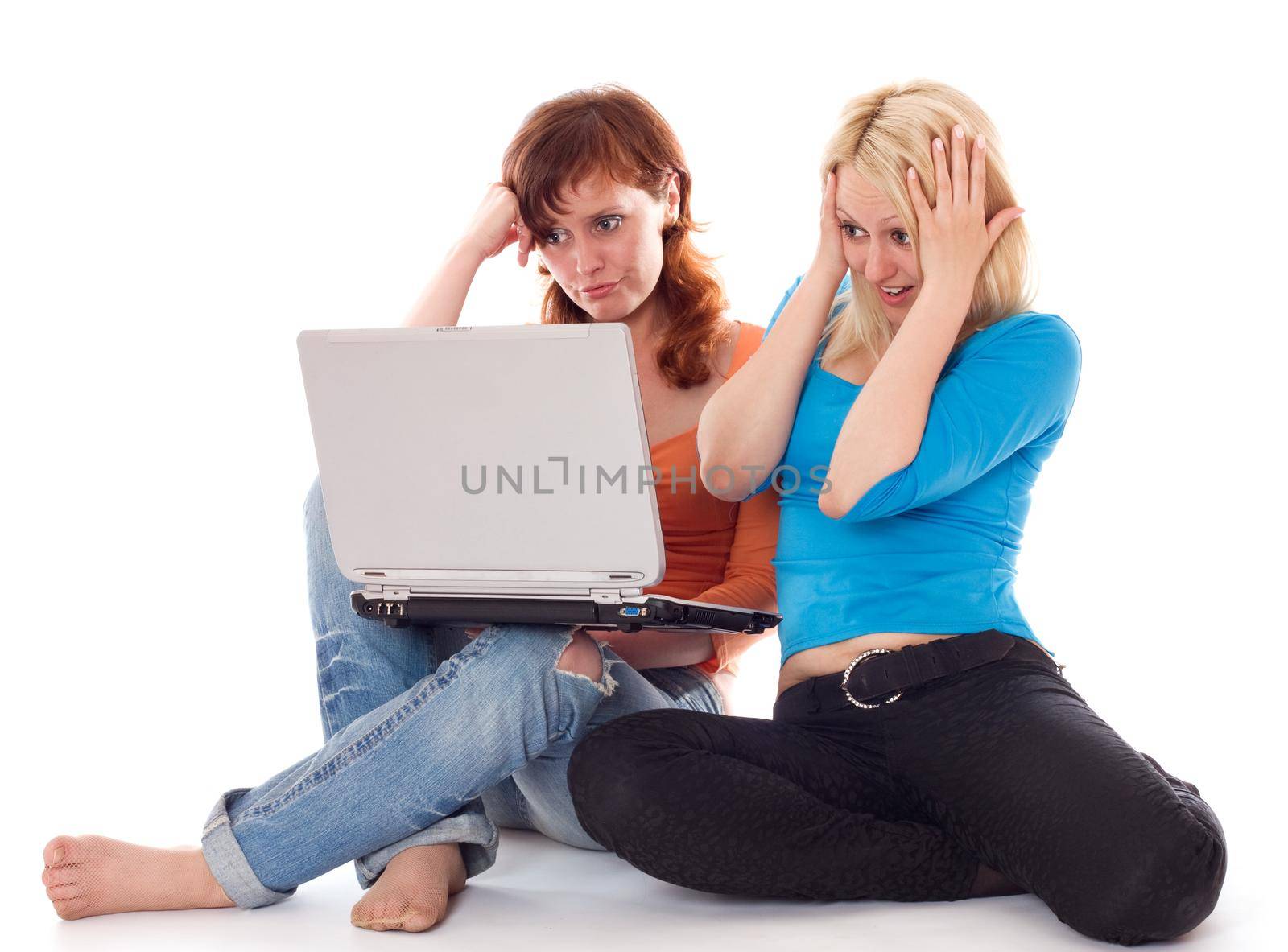 Two young women find something shocking on a laptop. Isolated on white.
