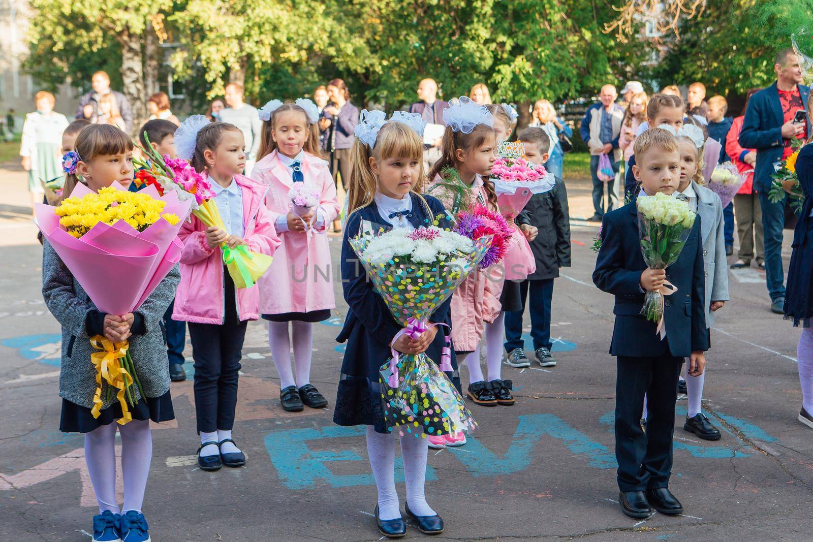 NOVOKUZNETSK, KEMEROVO REGION, RUSSIA - SEP, 1, 2021: Meeting with the first-grade pupils and teacher at schoolyard. The day of knowledge in Russia.