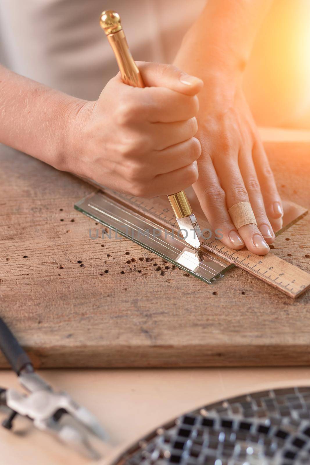 Artist cutting sheets of stained glass into small mosaic squares. Close-up by nazarovsergey