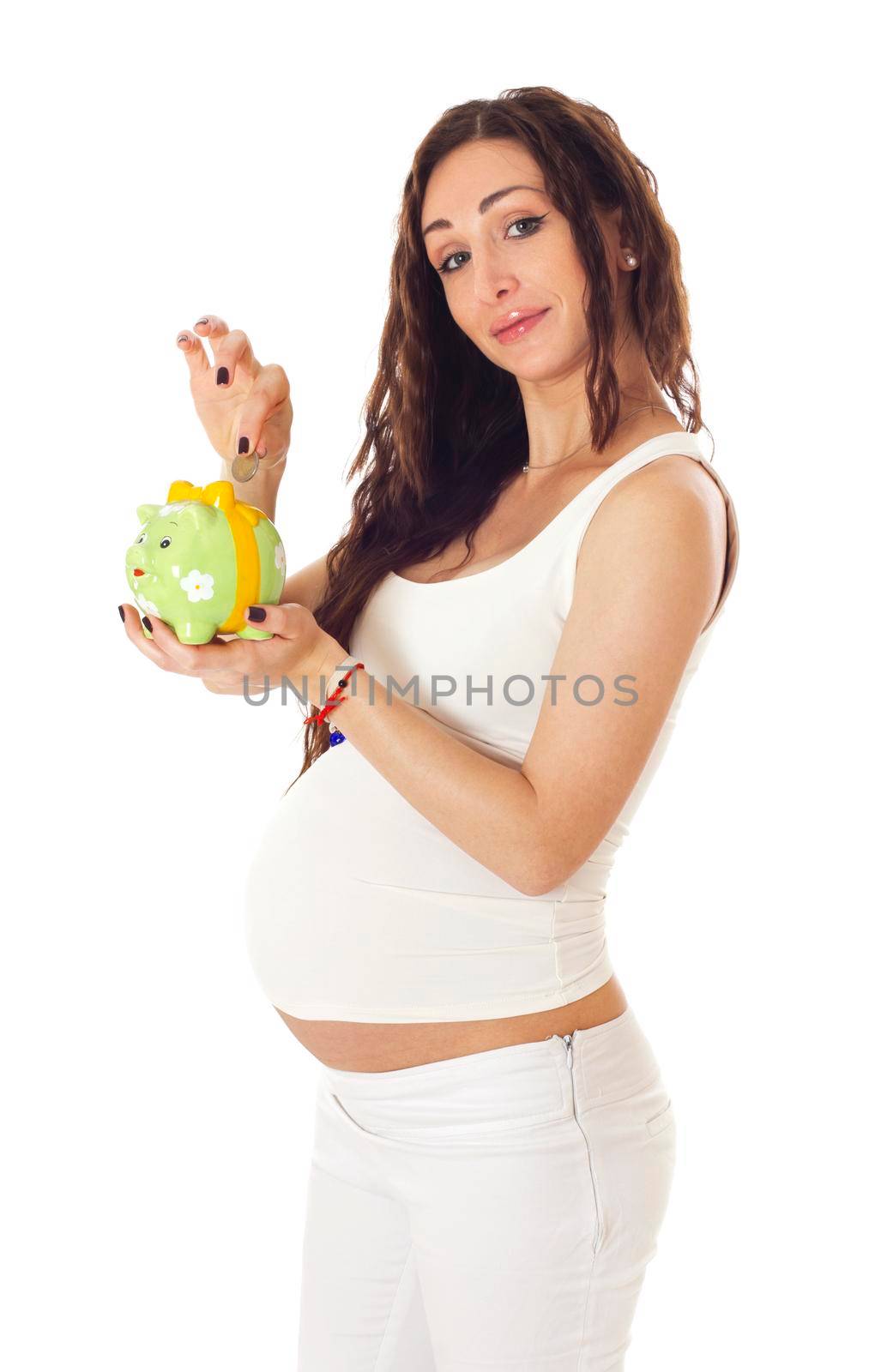 A woman putting money into a piggy bank in front of her pregnant belly. Isolated on white.