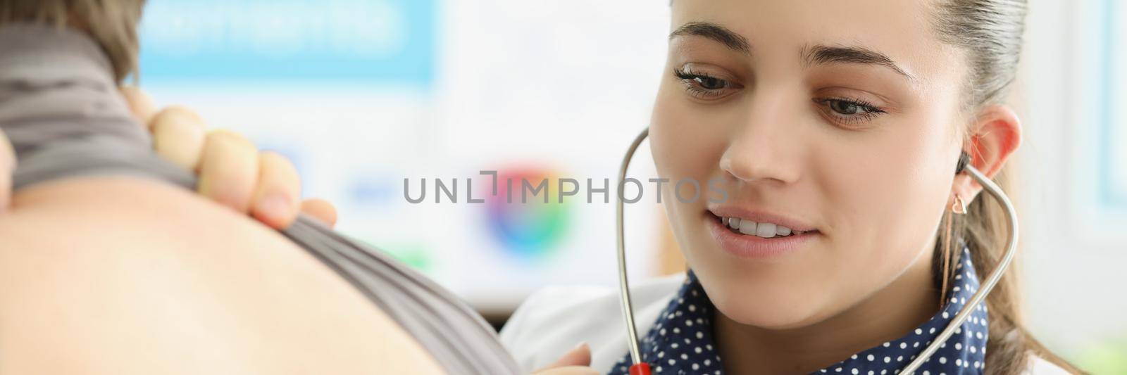 Portrait of young female doctor listen to patients back with stethoscope equipment. Concentrated medical worker examine body, diagnostic. Medicine concept