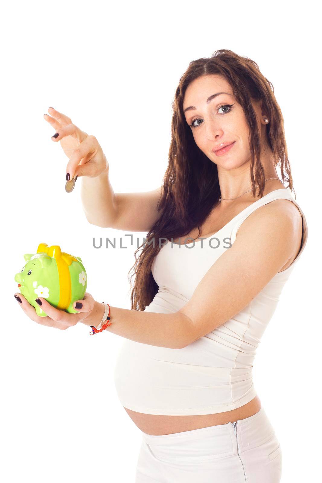 A woman putting money into a piggy bank in front of her pregnant belly. Isolated on white.