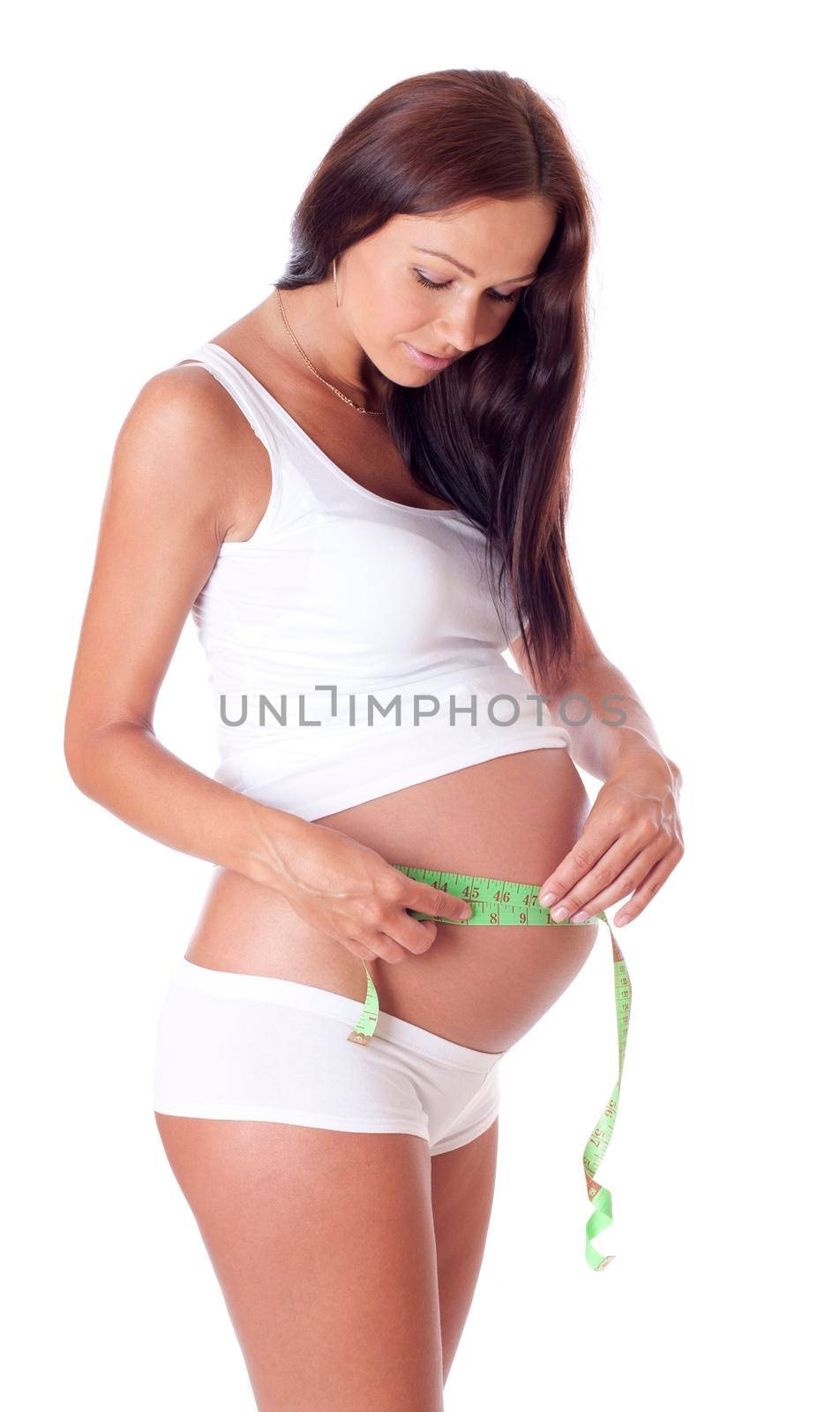 Beautiful smiling pregnant woman measures her tummy by tape measure - isolated on white