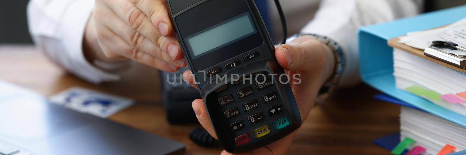 Close-up of man holding modern credit card reader machine for cashless payment. Empty screen for total cost and numbers on pad. Modern technology concept