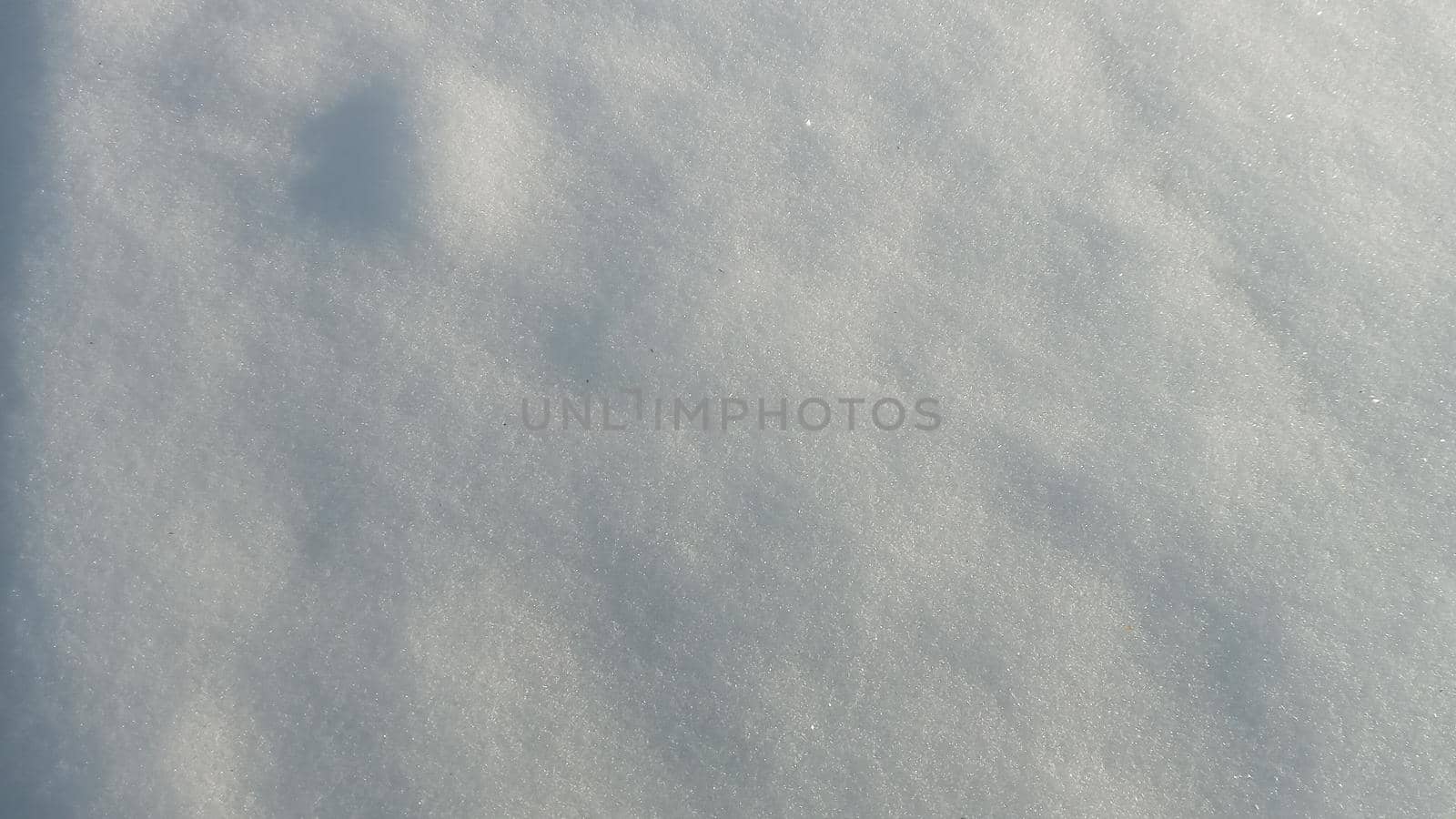 Background with natural snow texture, close-up view from above. Beautiful sunny bright texture of snow in winter season. Selective focus is used.