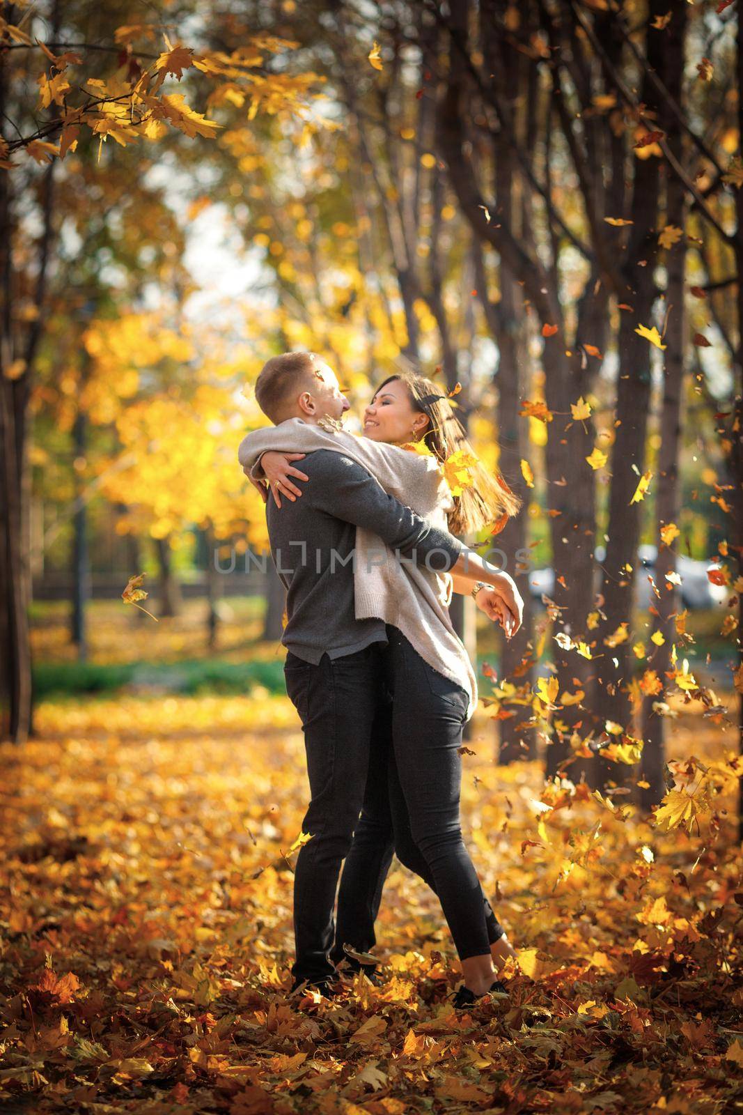 Romantic date in autumn park under leaf fall at sunset.