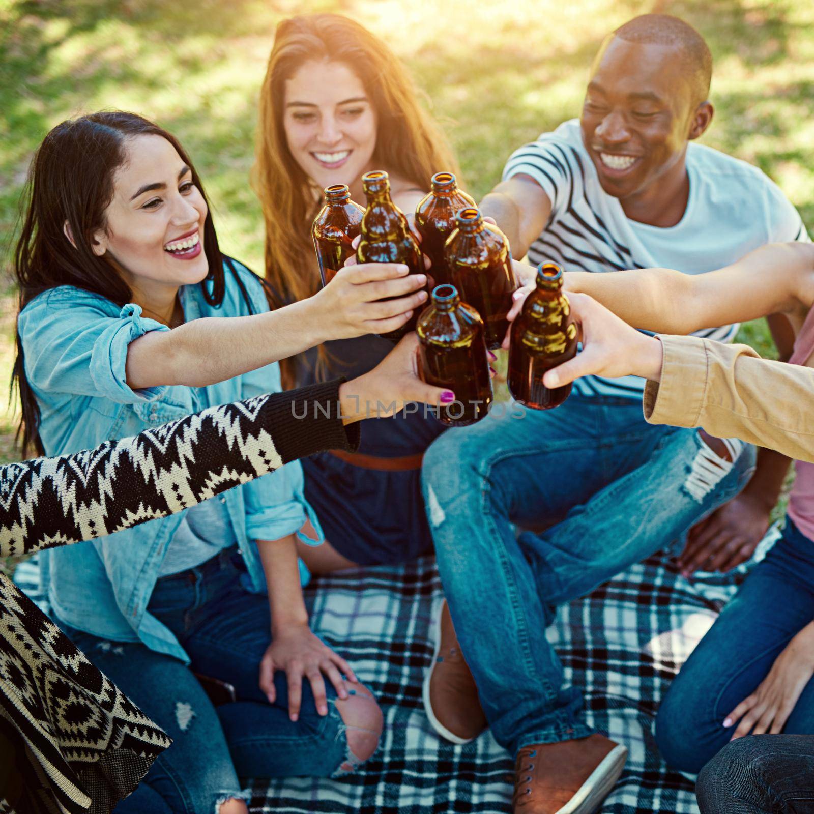 Cheers to lifelong friendships. Cropped shot of a group of friends having drinks while out on a picnic. by YuriArcurs