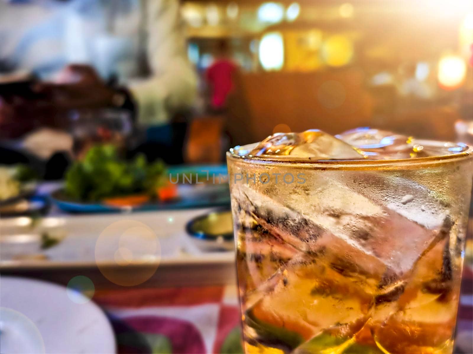 Glass of whiskey on ice with bottle on on table wooden bar background.