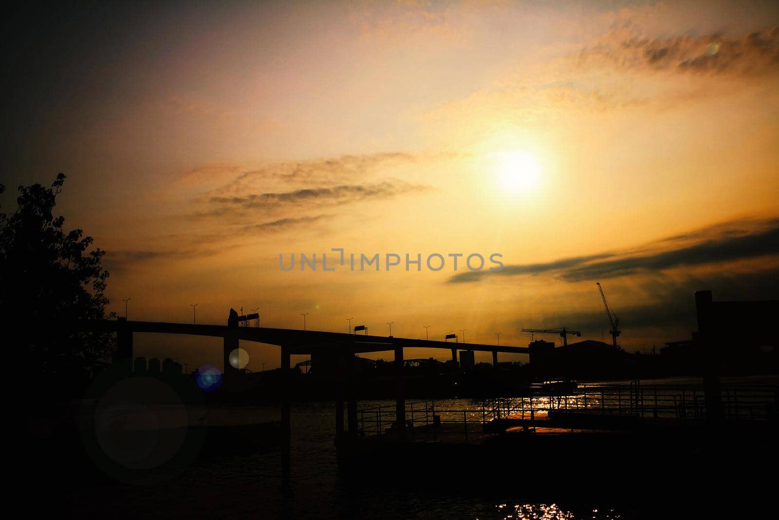 silhouette of skyline,river and bridge during sunset.