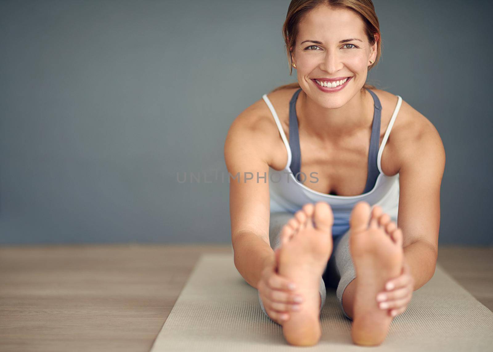 Smile, breathe and go slowly. Portrait of a young woman doing yoga. by YuriArcurs