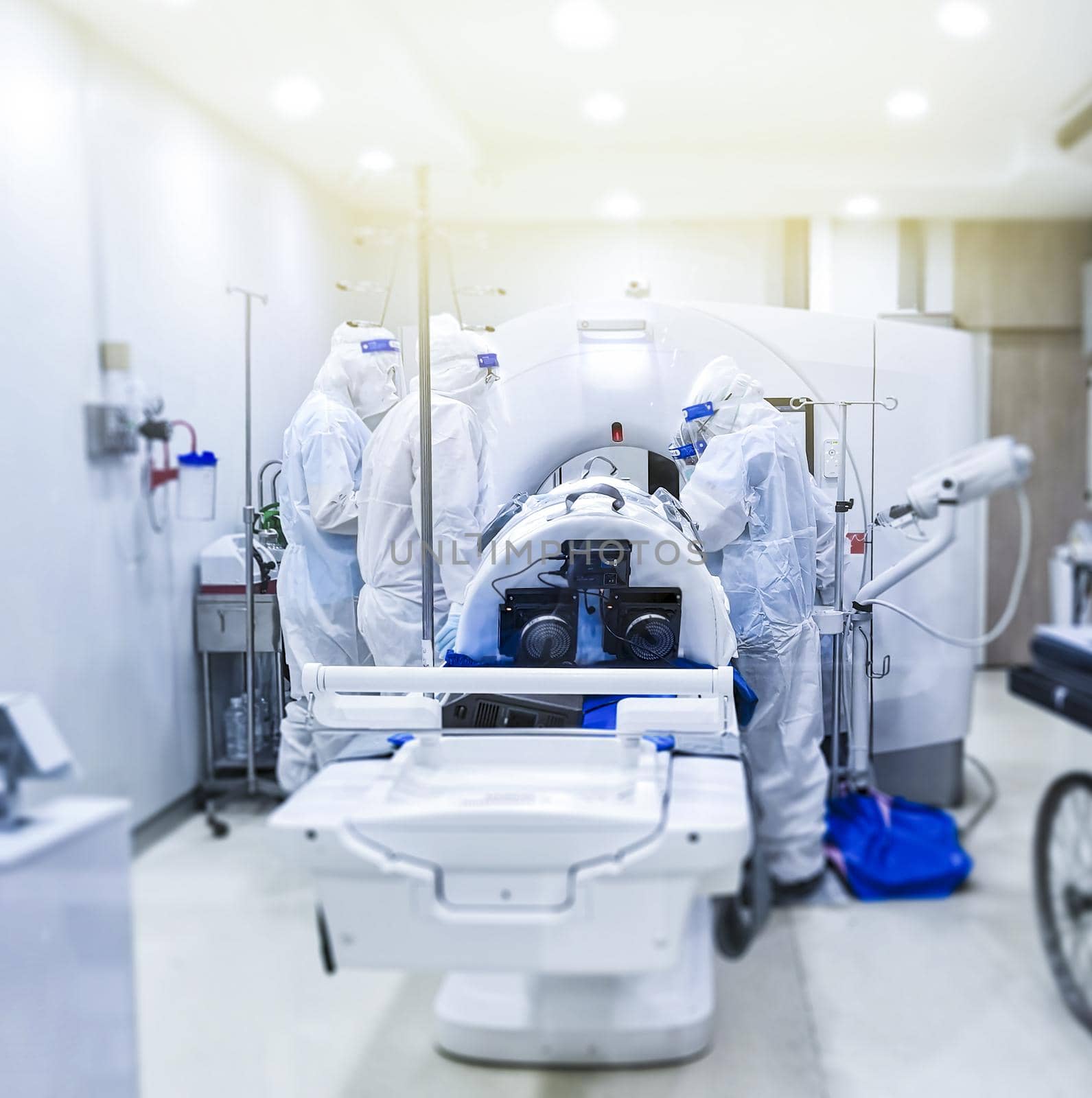 The technician and team in coverall using CT Scanner for examining patient coronavirus during global pandemic. Medical team wearing protective suit PPE.