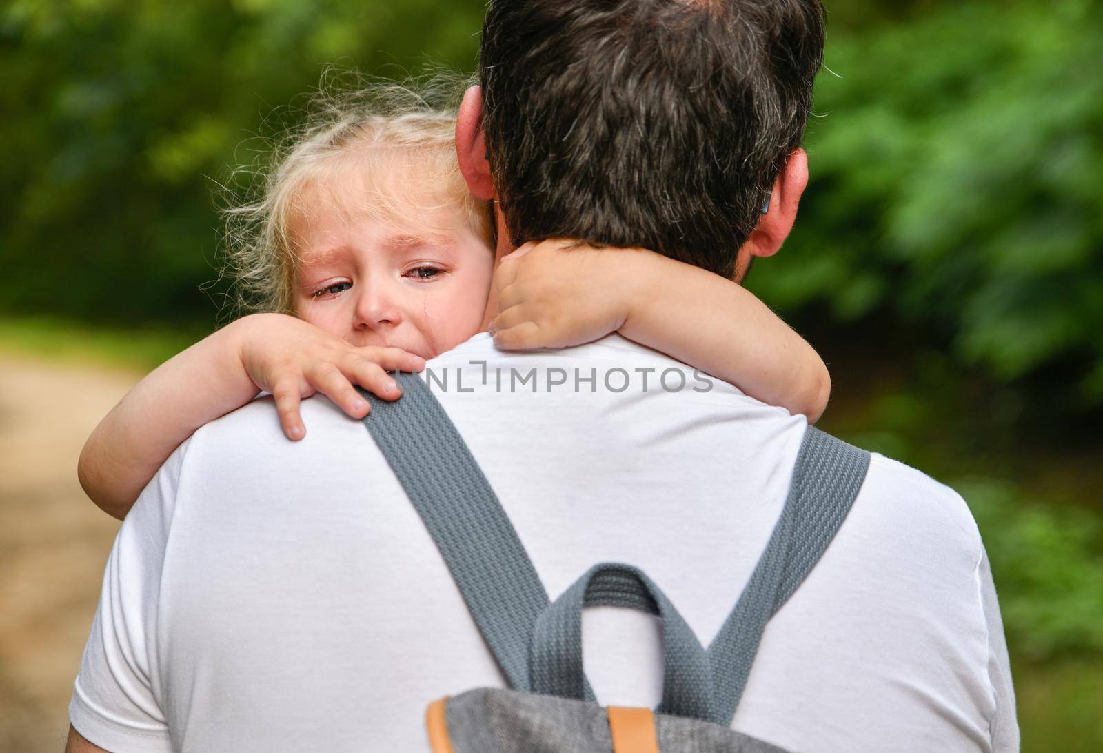 A little girl cries and hugs her father
