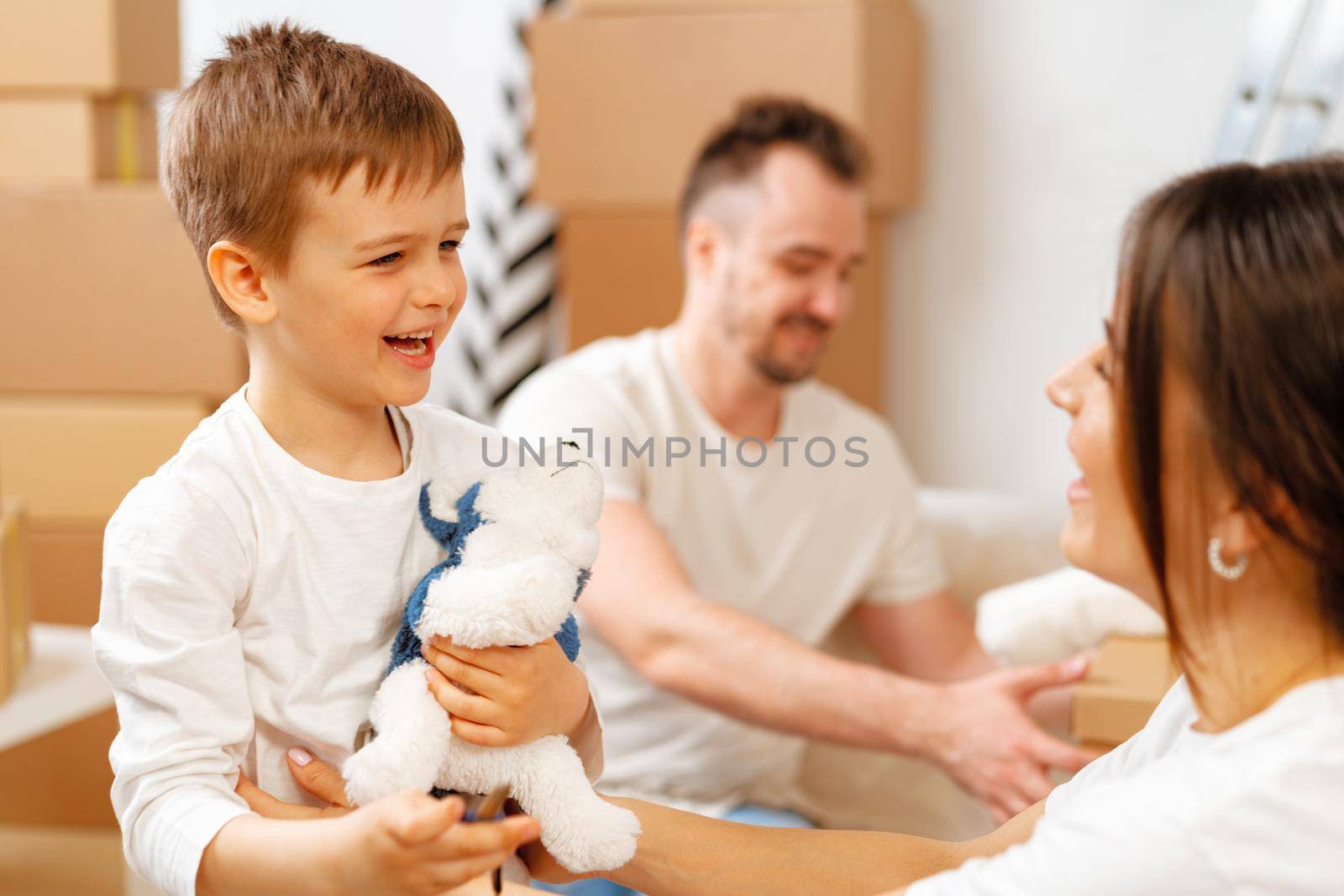 Portrait of happy family with cardboard boxes in new house at moving day by Fabrikasimf