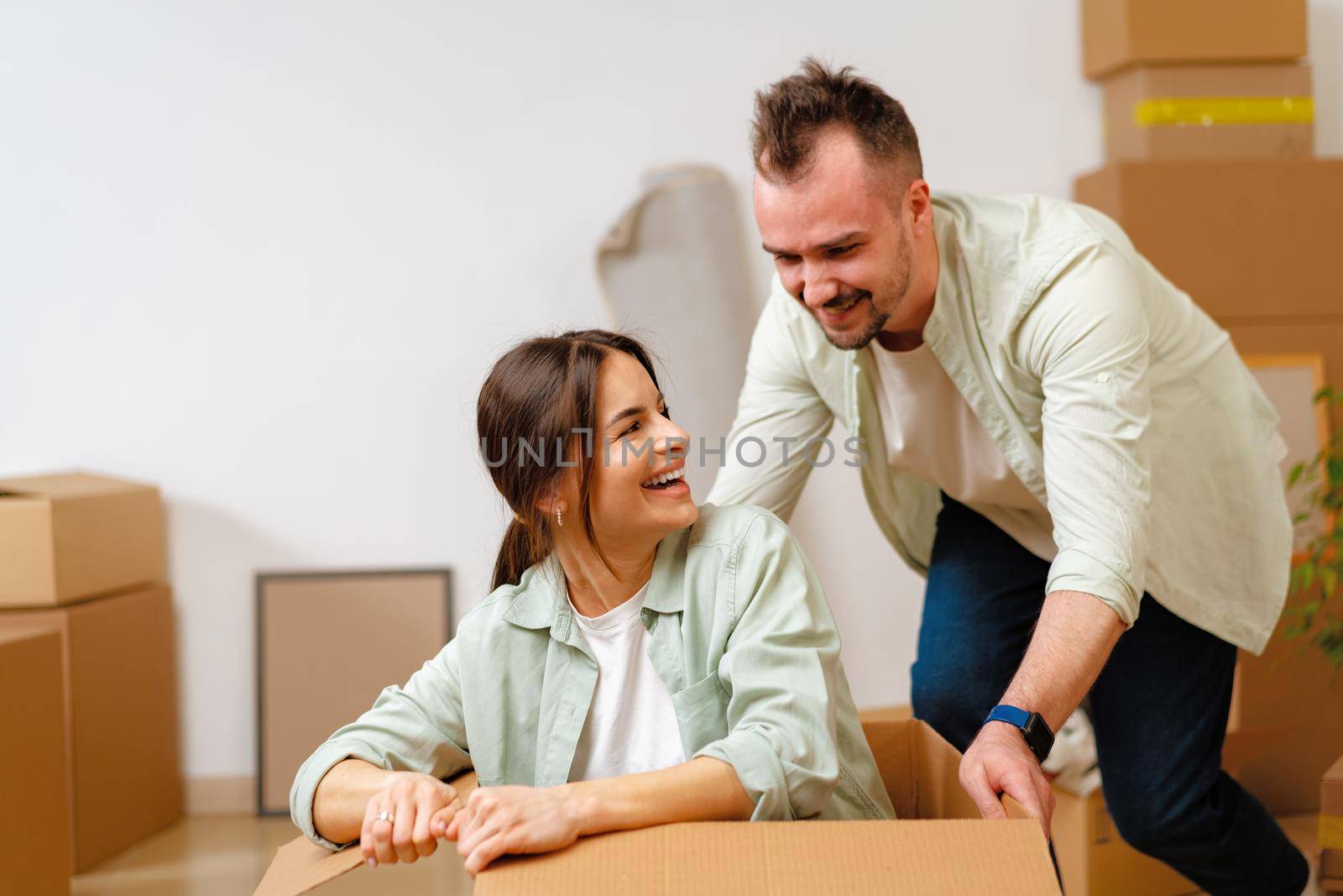 Young happy couple in room with moving boxes at new home by Fabrikasimf