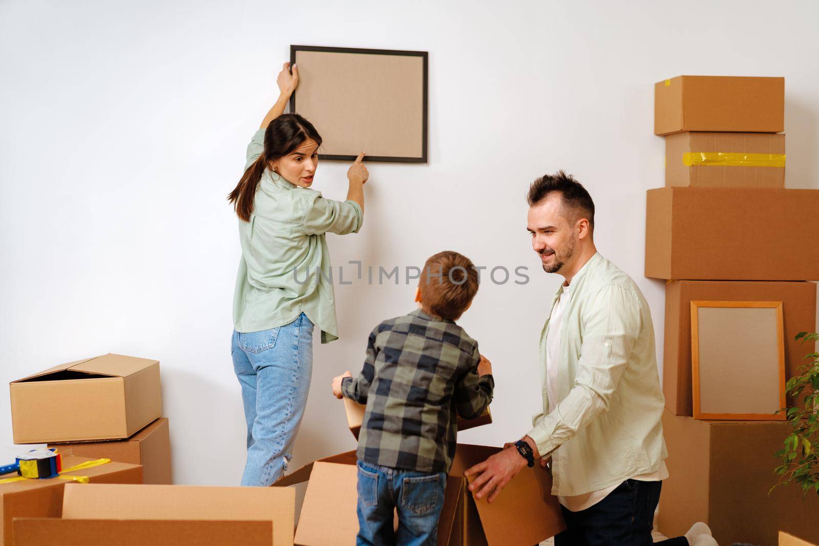 Young parents and son having fun during moving day to new house, portrait