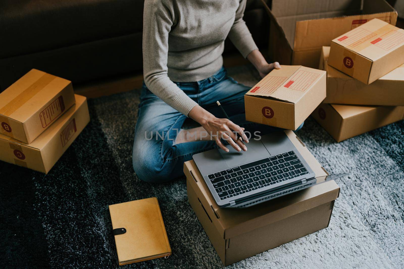 Asian female online store small business owner entrepreneur seller packing shipping ecommerce box checking website retail order using laptop preparing delivery parcel on table. Dropshipping concept