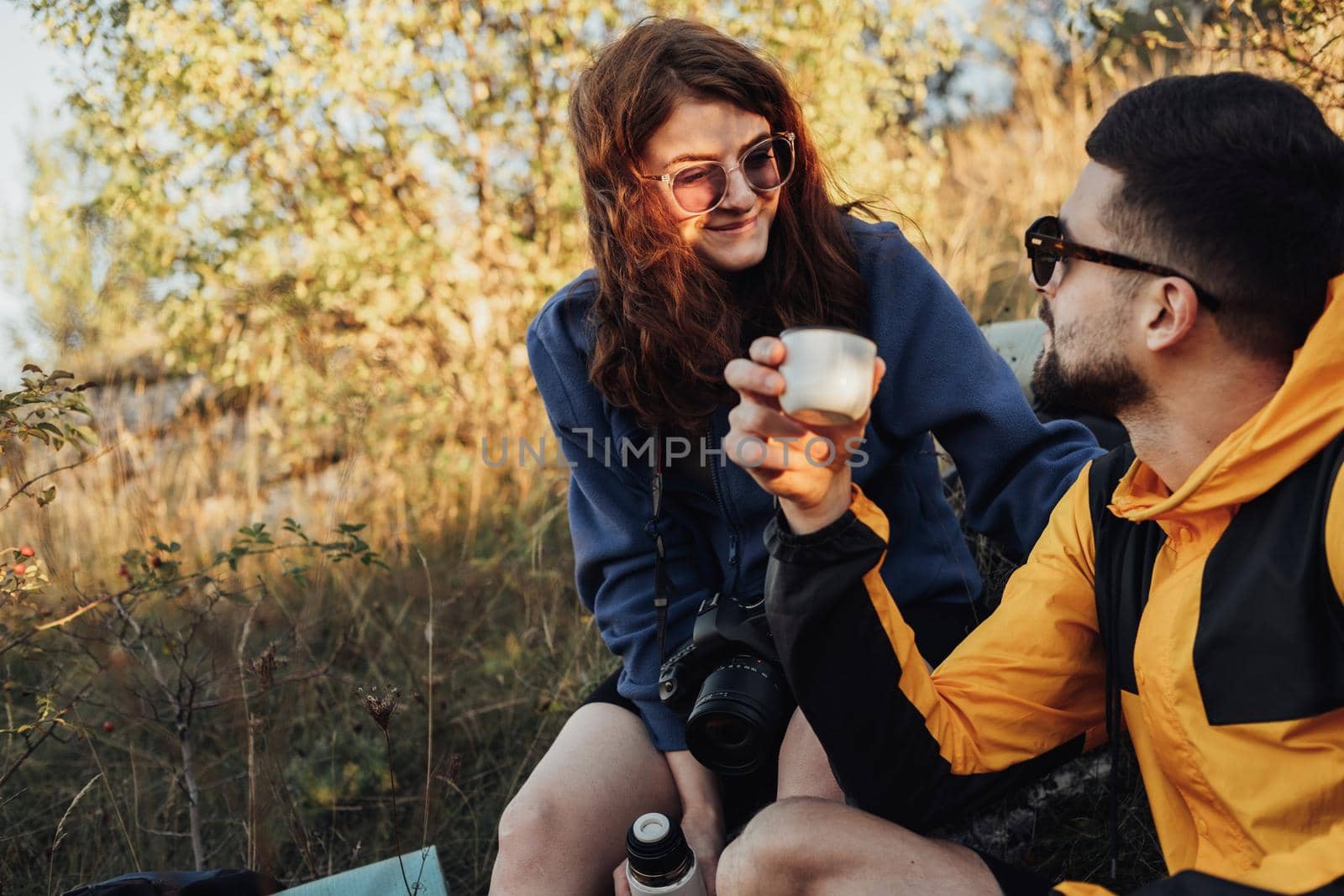 Man and Woman Young Travel Couple Made a Stop During the Hike to Drink Hot Tea from the Thermos by Romvy