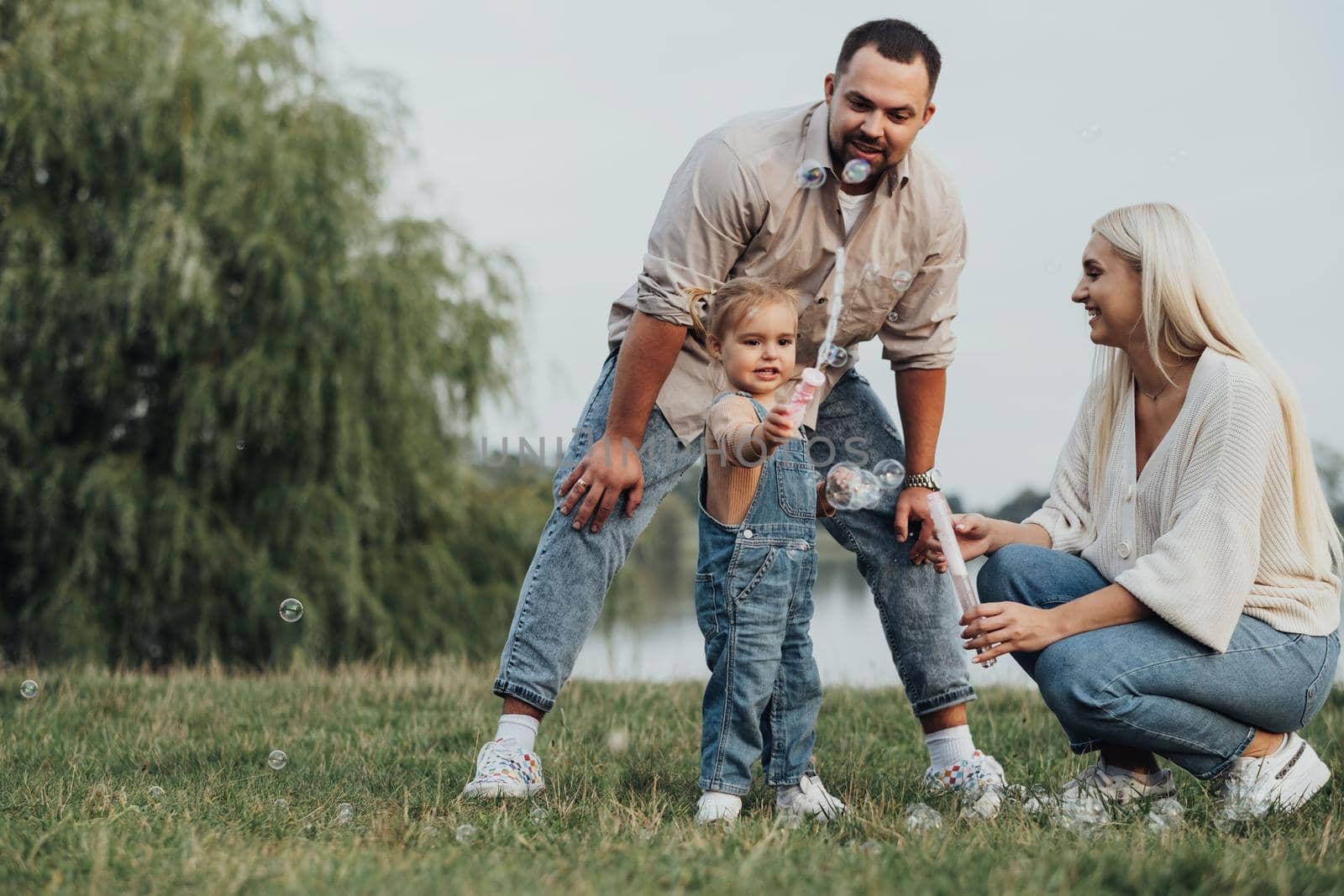 Portrait of Happy Young Family, Mom and Dad with Their Little Daughter Having Fun Outdoors Outside City