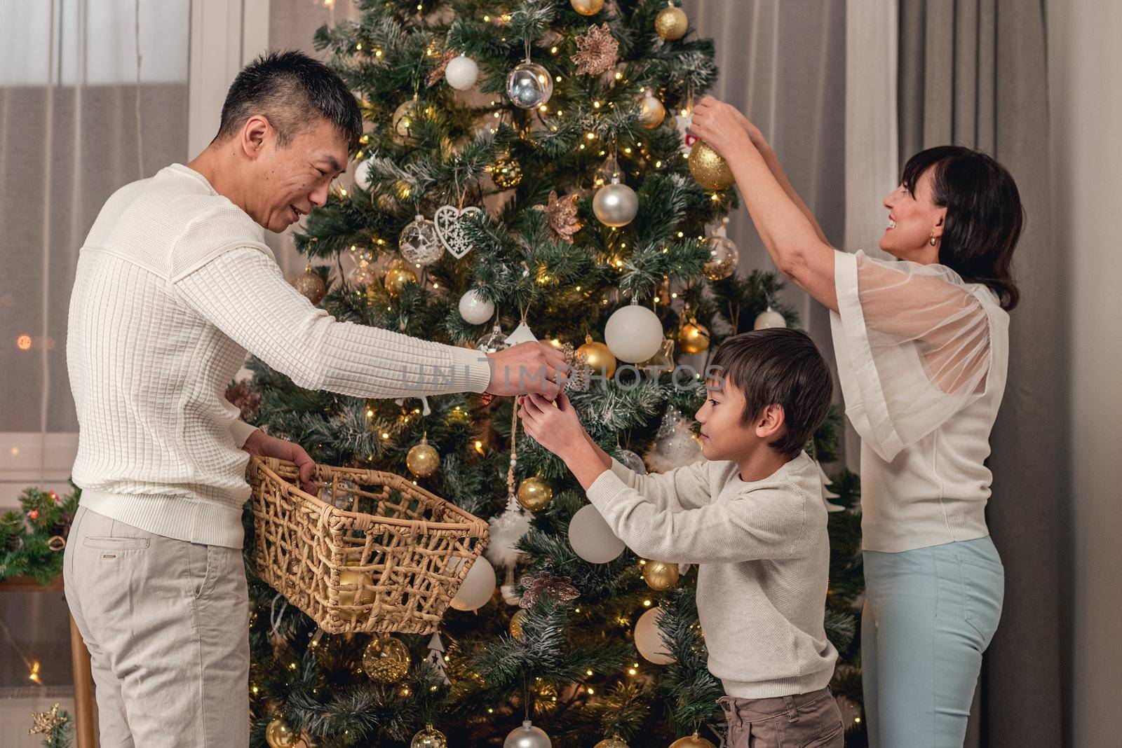 Happy family decorating christmas tree together by tan4ikk1