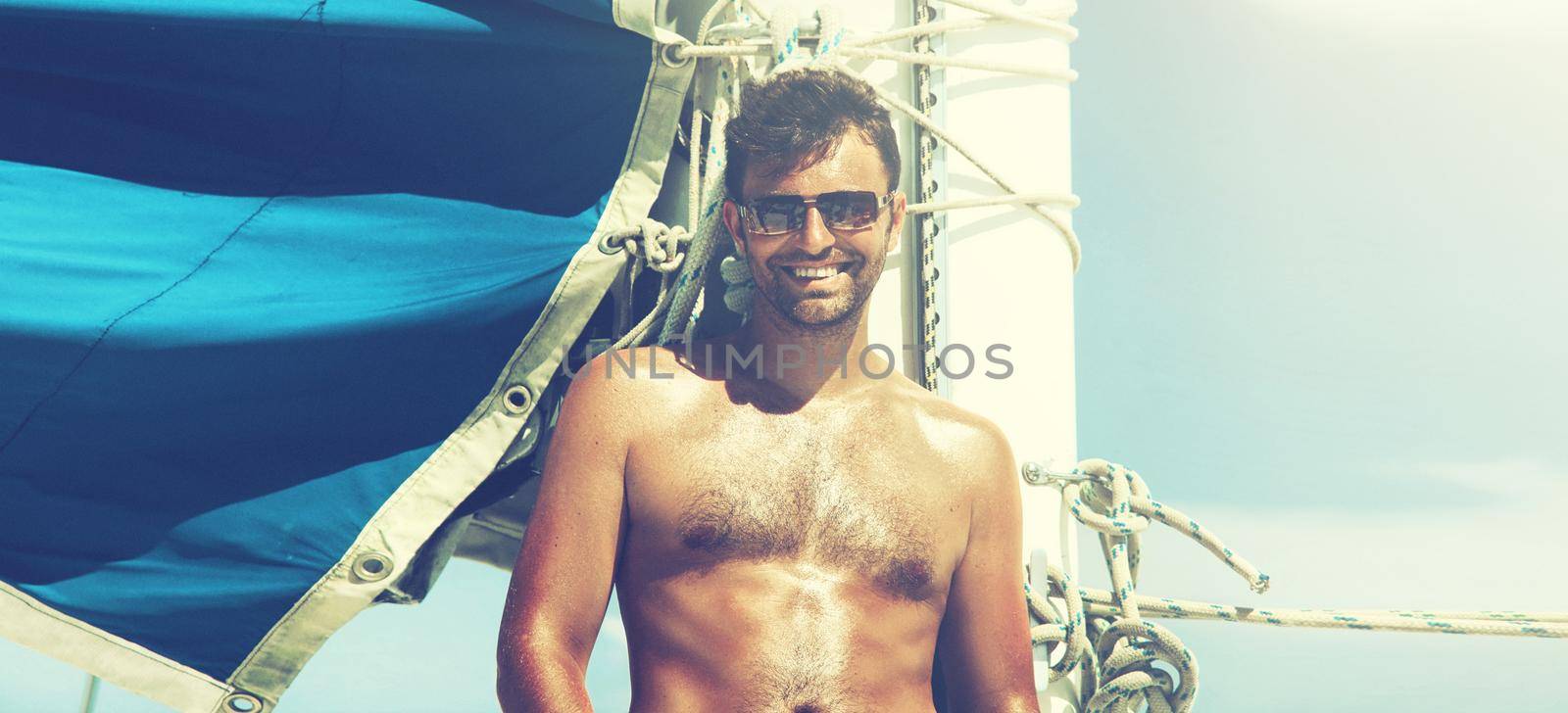 Young man sailing his boat on the open ocean by Taut