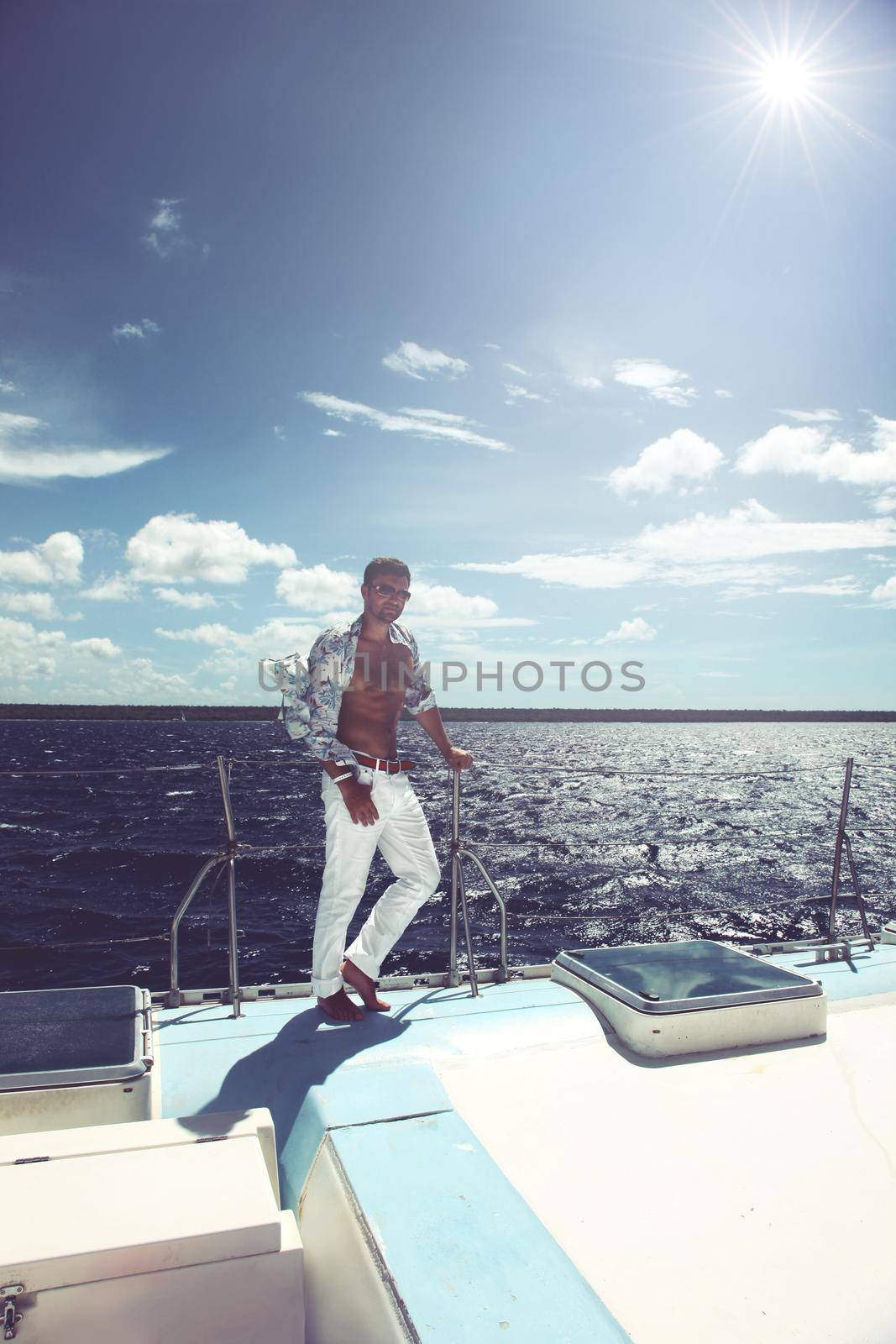 Young man sailing his boat on the open ocean by Taut