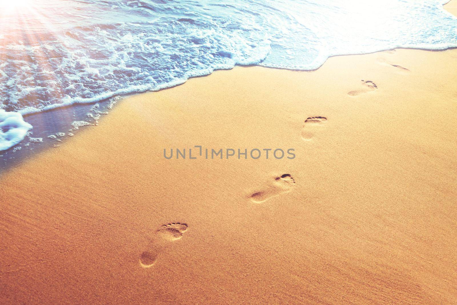 Detail of human feet in the golden sand at the beach. Summer travel and vacation concept.