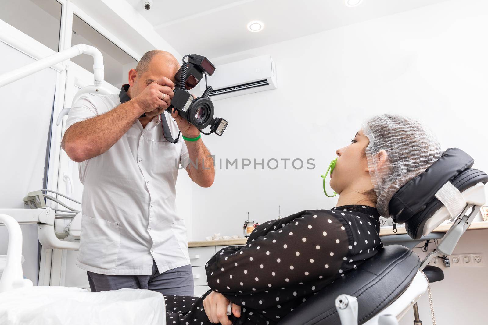 Dentist taking picture of mouth, his work on teeth of female patient