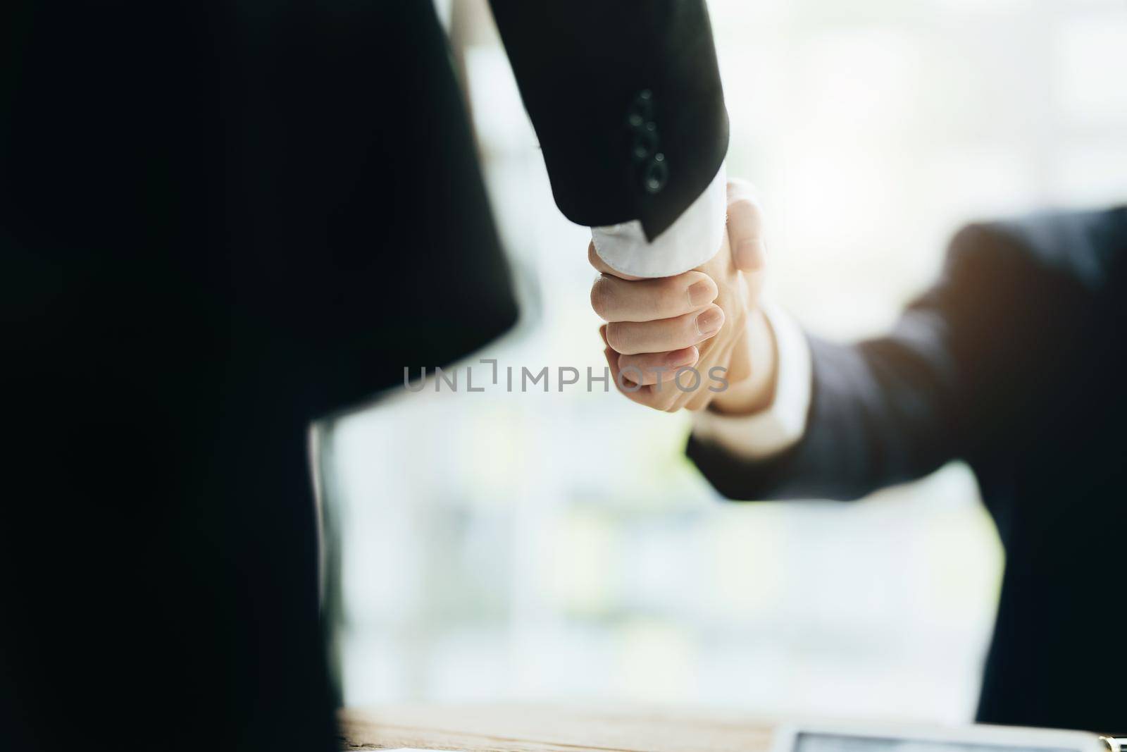 Asian entrepreneurs handshakes to congratulate the agreement between the two companies to enhance investment and financial strength. deal concept by Manastrong